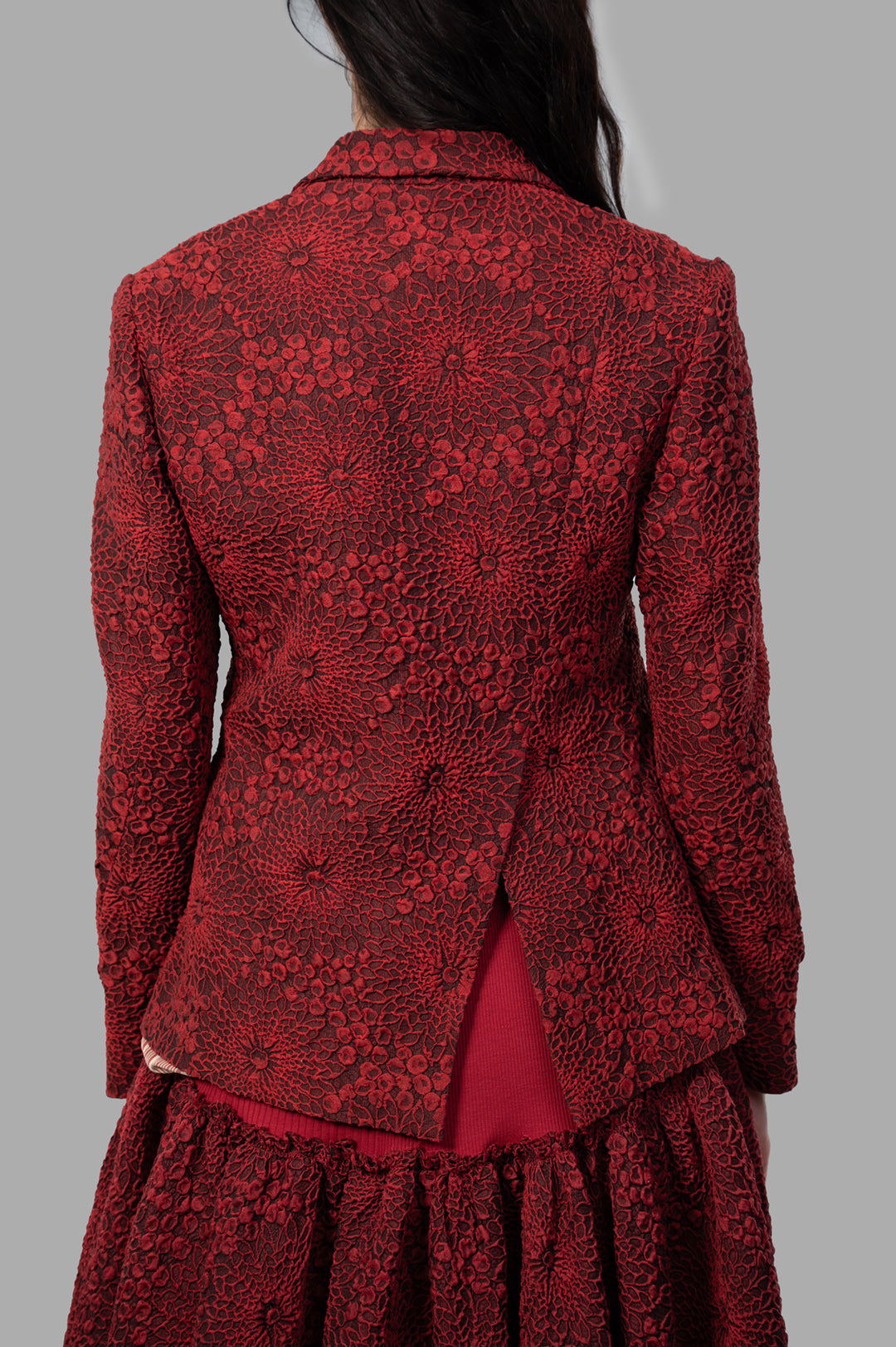 Marc Point Floral Jacket in red, showcasing intricate floral texture and asymmetrical back design on-model.