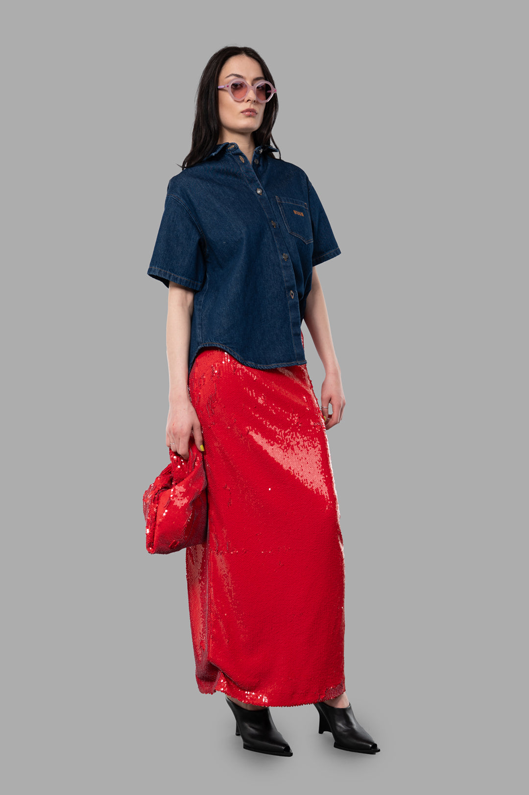 MSGM Red Sequin Skirt on model, full-length view with denim shirt and matching clutch, showcasing bold style.