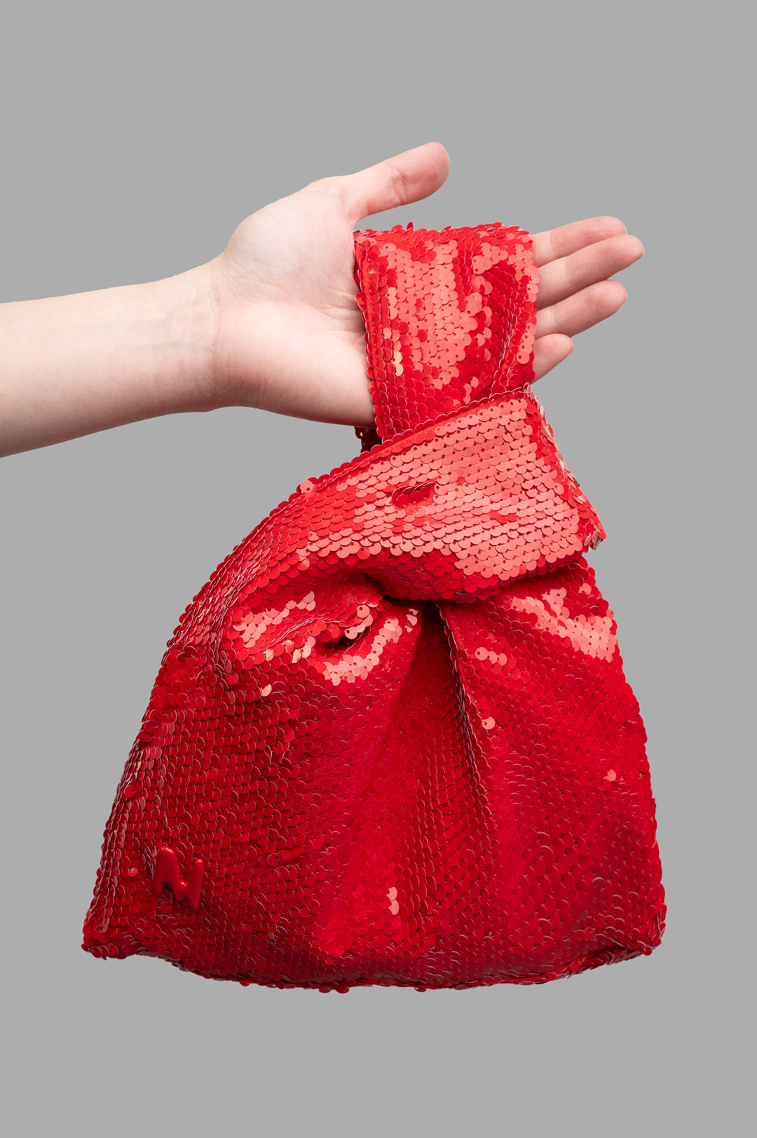 MSGM Red Paillettes Bag held in hand, showcasing vibrant sequins and unique knot design, perfect for contemporary style.