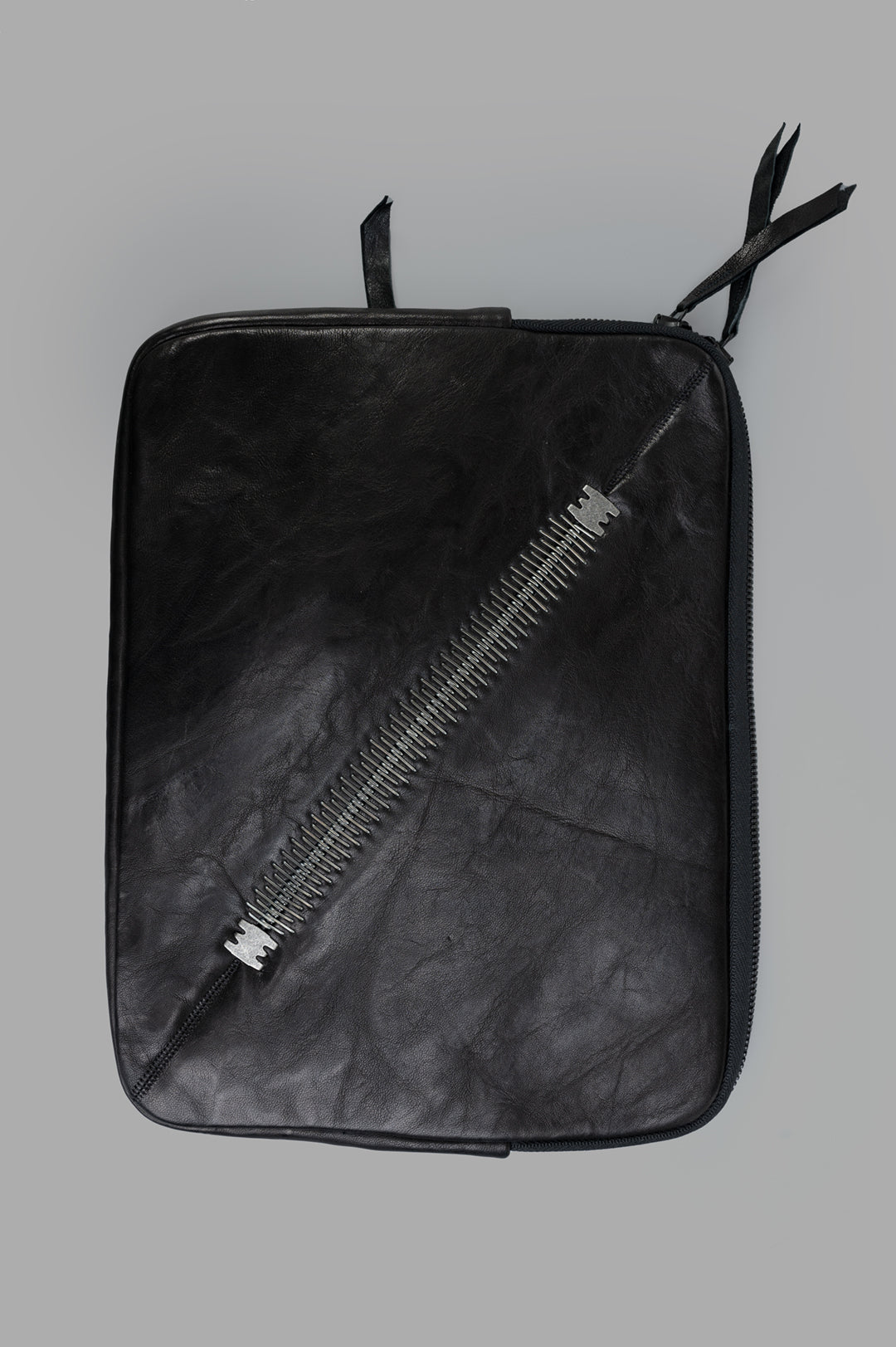 Isaac Sellam Leather Laptop Pouch, black, front view with double-opening zip and signature spine detailing.