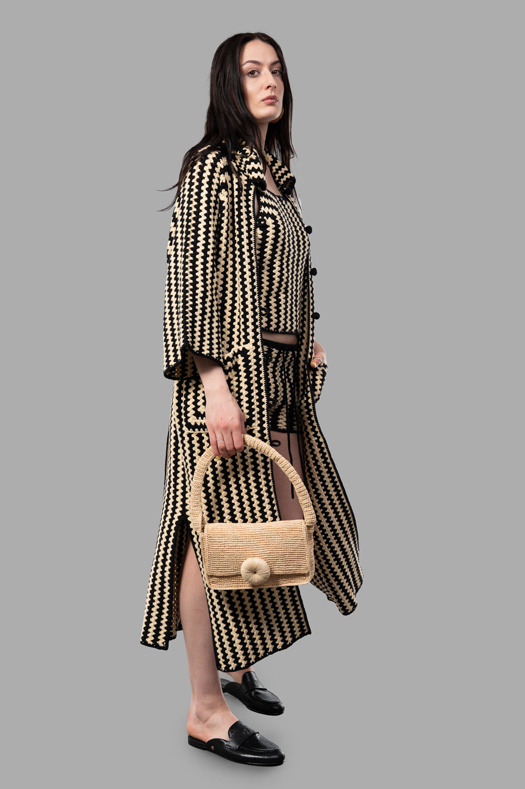 By Malene Birger Miro Shoulder Bag held by model, showcasing the handcrafted raffia design with floral appliqué detail.