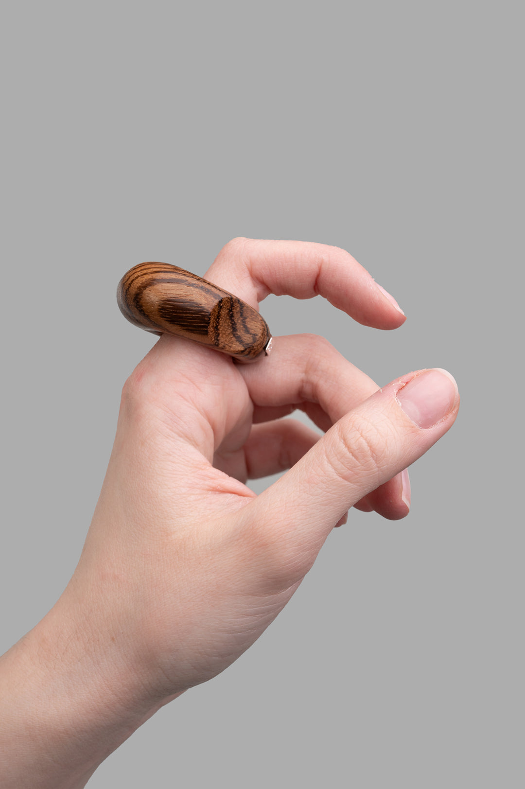 Monies Roris Ring showcased on a hand, highlighting its intricate wood design and smooth, natural finish in rich brown tones.