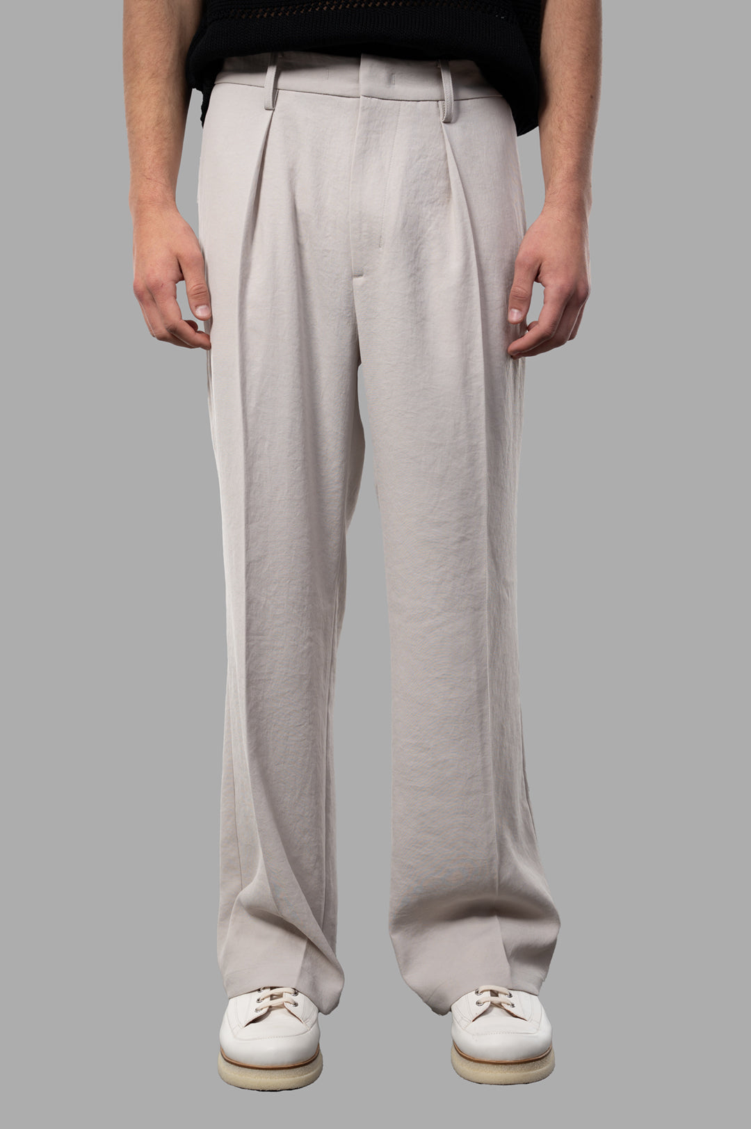Vein Pleated Trousers in beige, showcasing relaxed fit and sleek pleats, worn by model, highlighting soft texture.