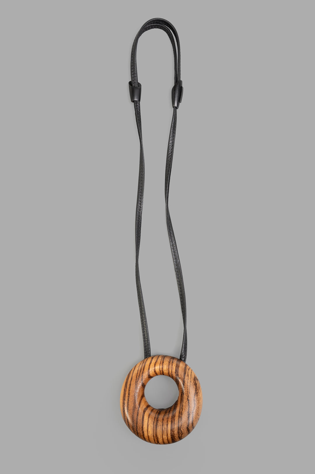Monies Vala Striped Pendant, close-up view, featuring a round brown wood design on a black cord necklace.