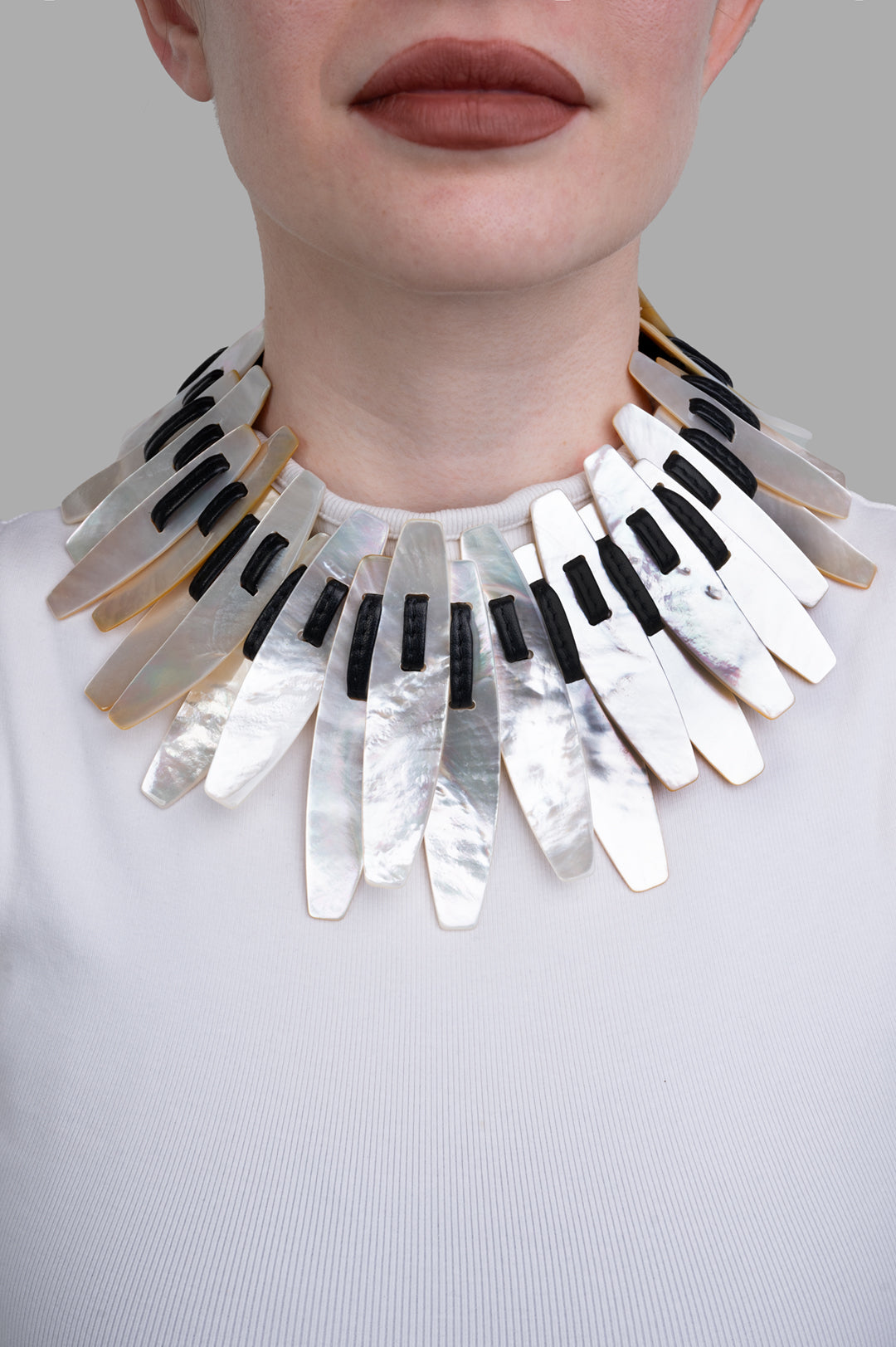 Monies Mother of Pearl Necklace displayed on model; features sleek, glossy white and black elements with artistic flair.