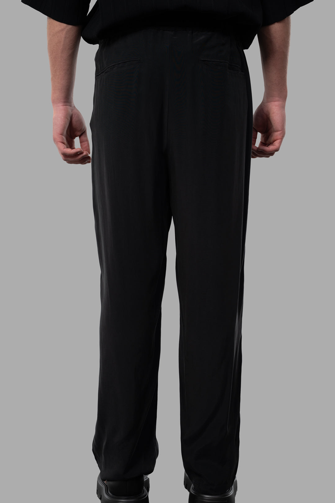 Attachment Pleated Trousers showcased from the back, featuring a sleek design and convenient back pockets in black.
