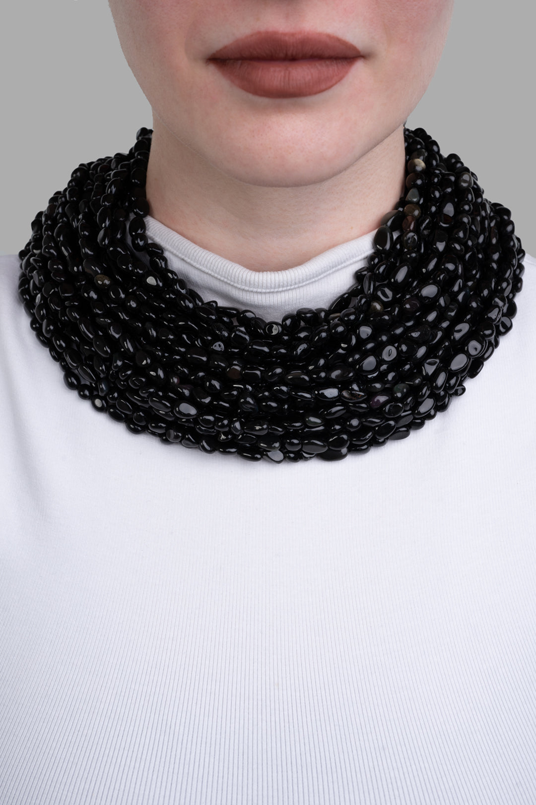 Monies Beaded Necklace displayed elegantly on a model, showcasing multiple strands of glossy black beads.