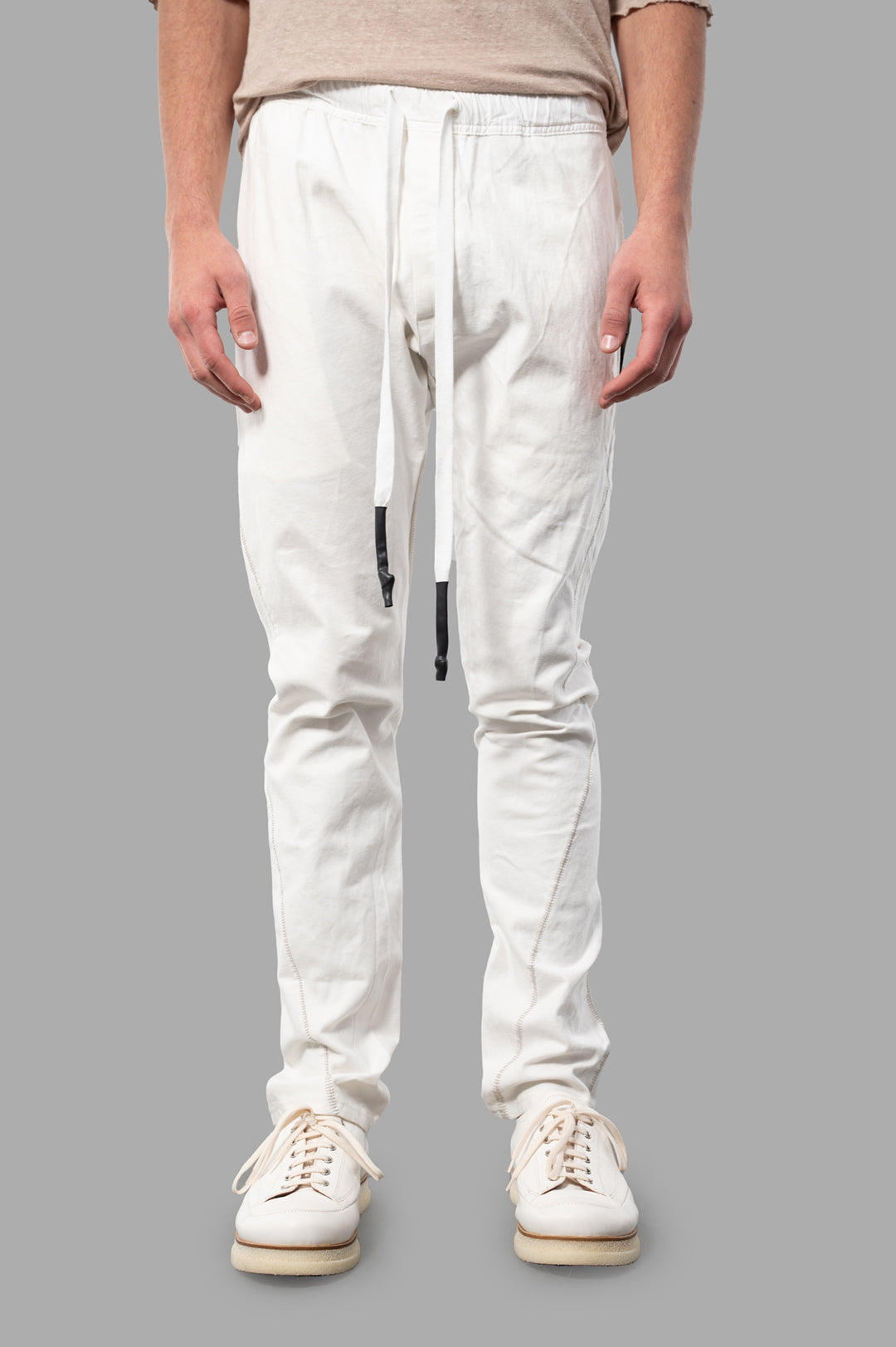 Isaac Sellam Drawstring Trousers in white, featuring a relaxed fit and elegant detailing, shown on-model from the front.