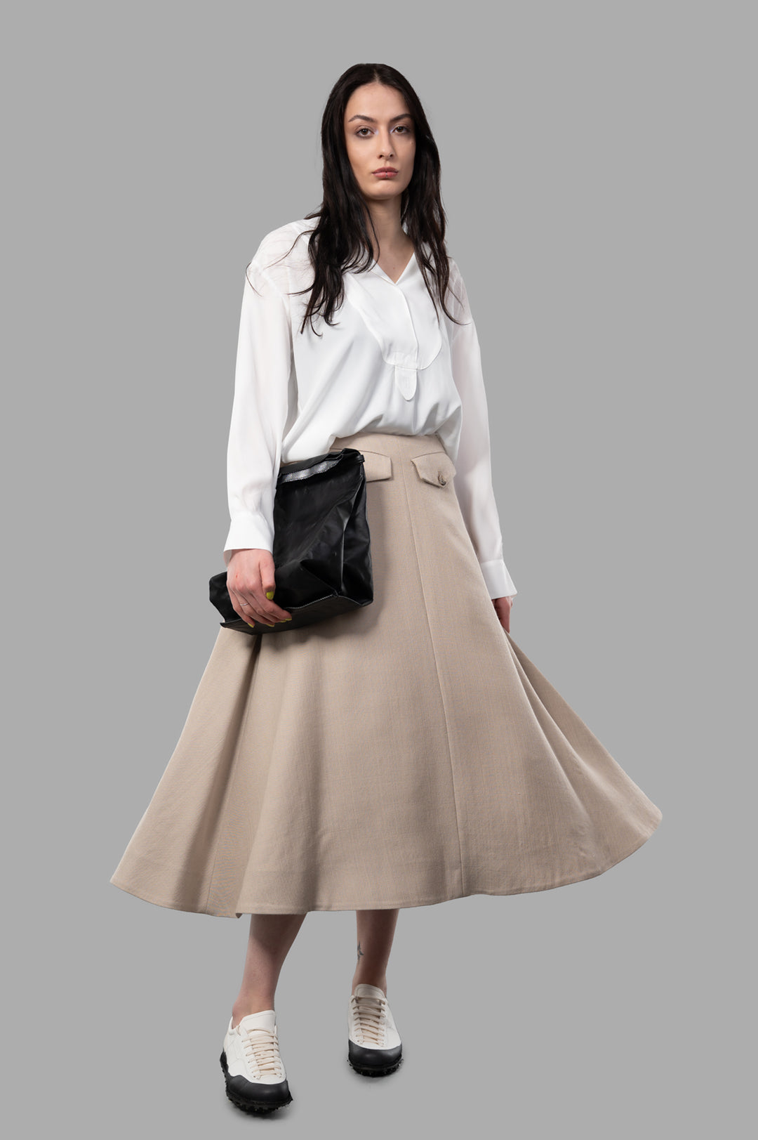 By Malene Birger Isella Midi Skirt on model, showing beige A-line design, front flap pockets, fluid wool-viscose blend.