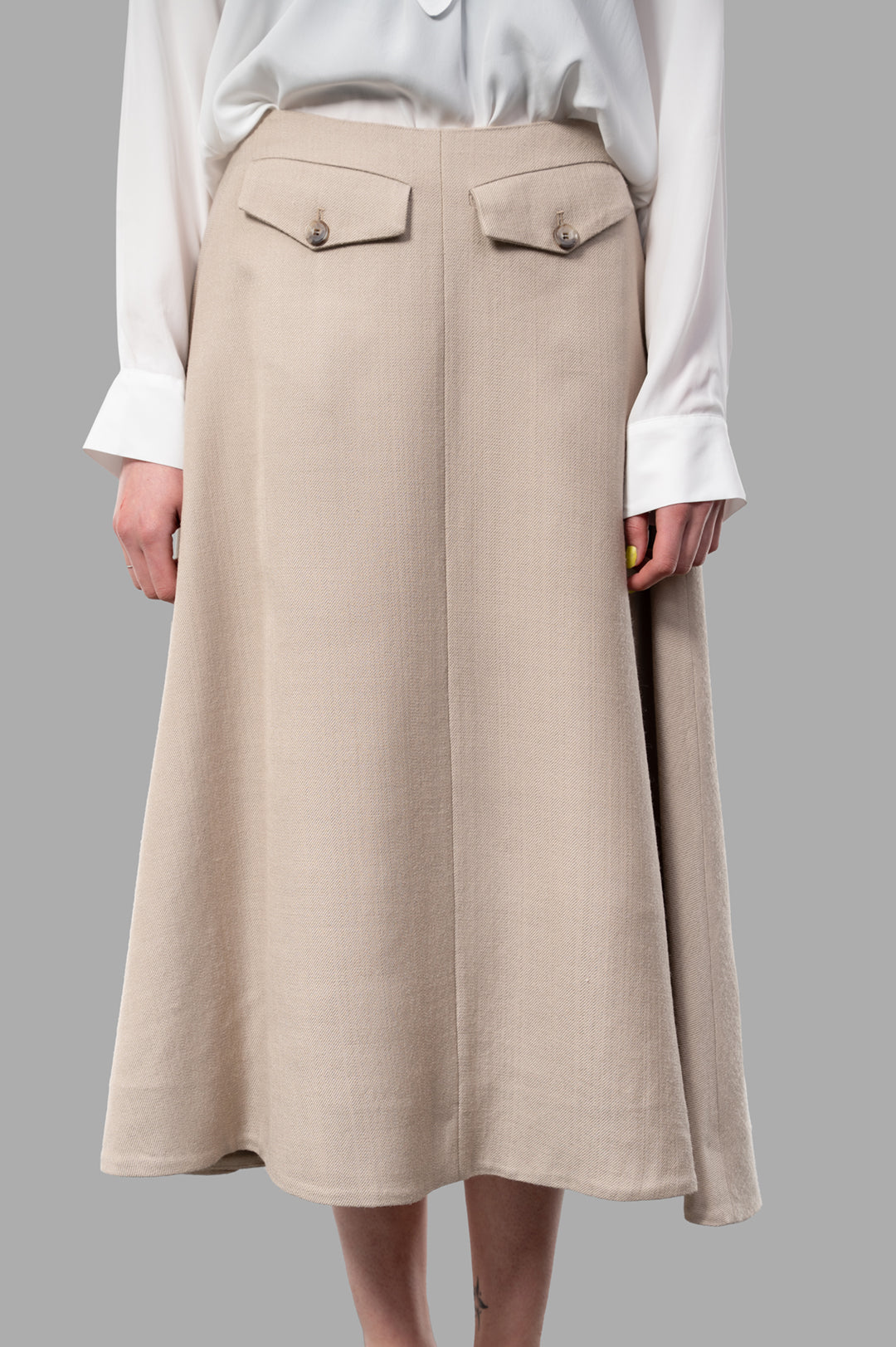 By Malene Birger Isella Midi Skirt in beige, featuring A-line silhouette and front flap pockets, displayed on a model.
