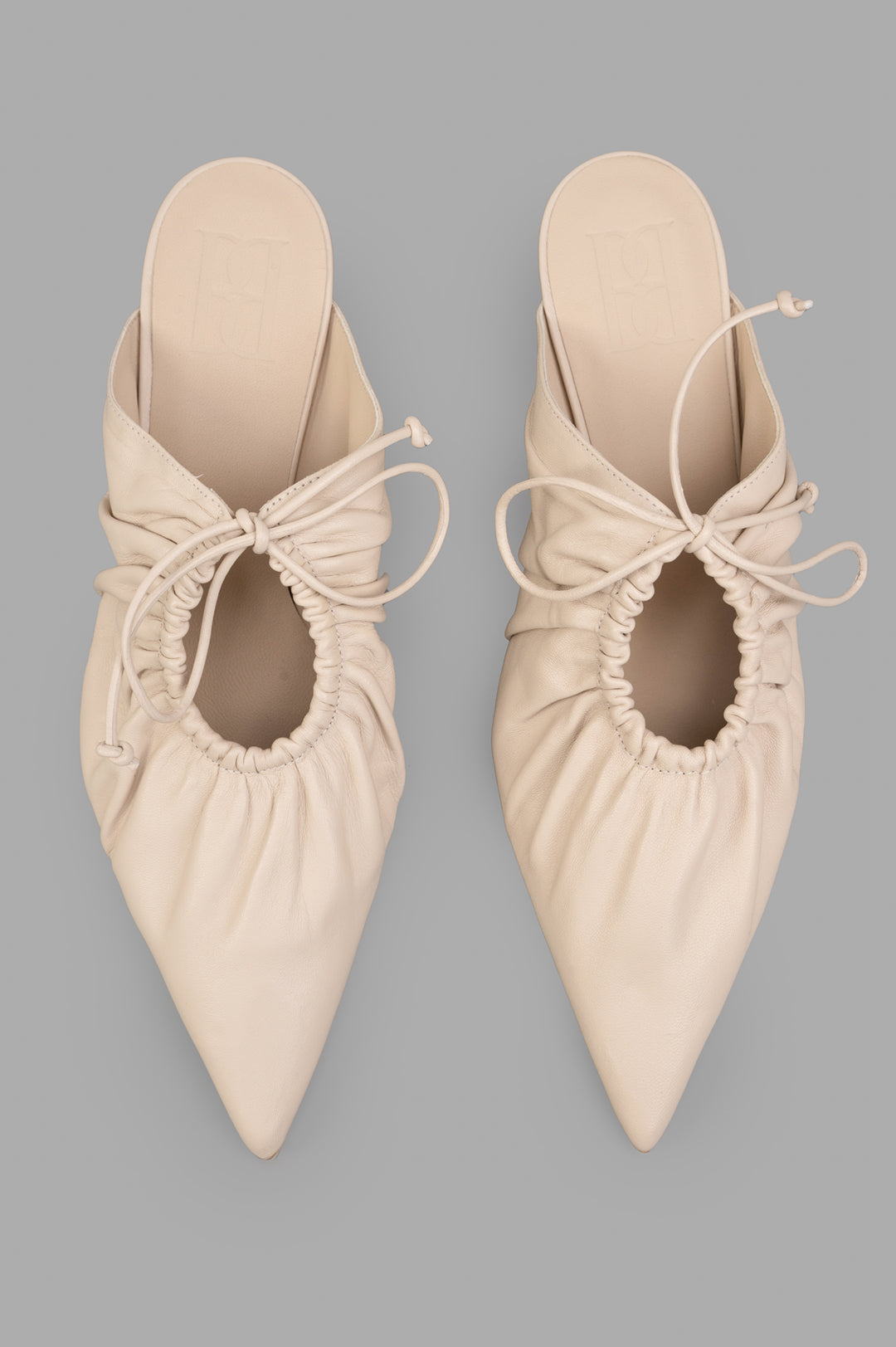 By Malene Birger Masey Leather Mules in ecru, featuring smooth goat leather, pointy silhouette, and bow detail. Top view.
