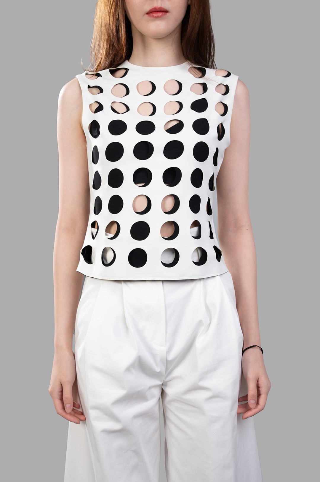 A.W.A.K.E. MODE Top with Layered Holes features a sleeveless design and layered cut-out detail, shown on a model in white.