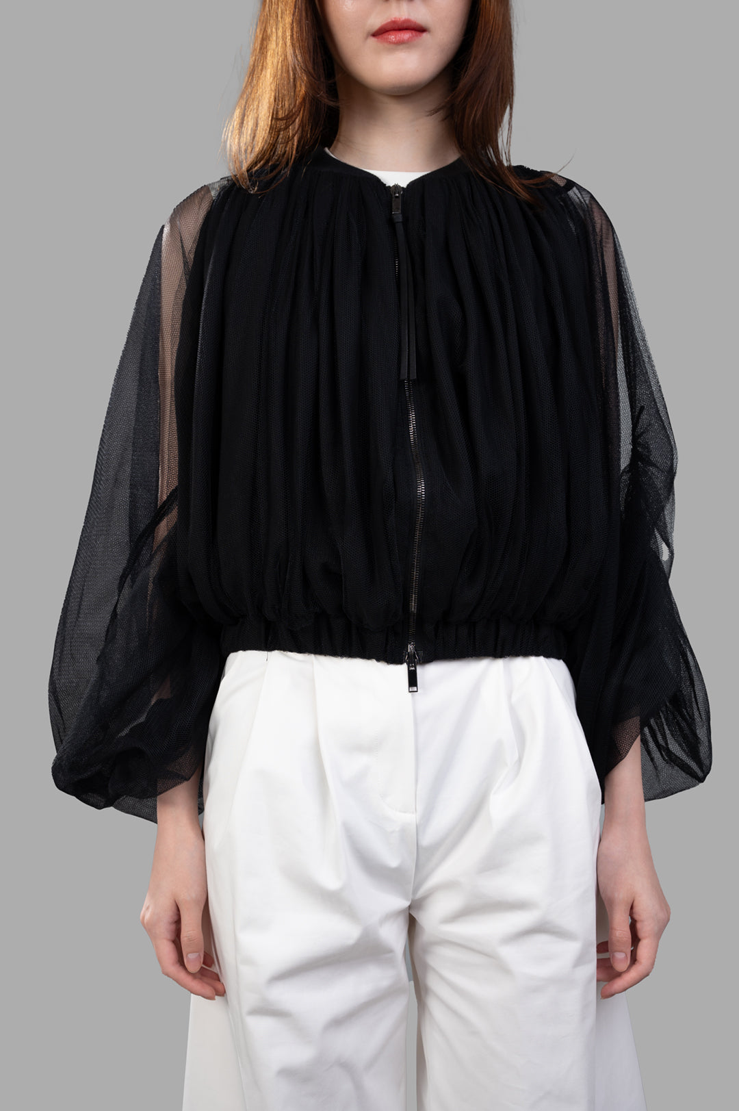 Giovanni Cavagna Mesh Bomber Jacket in black, featuring a relaxed fit with sheer sleeves, modeled with white trousers.
