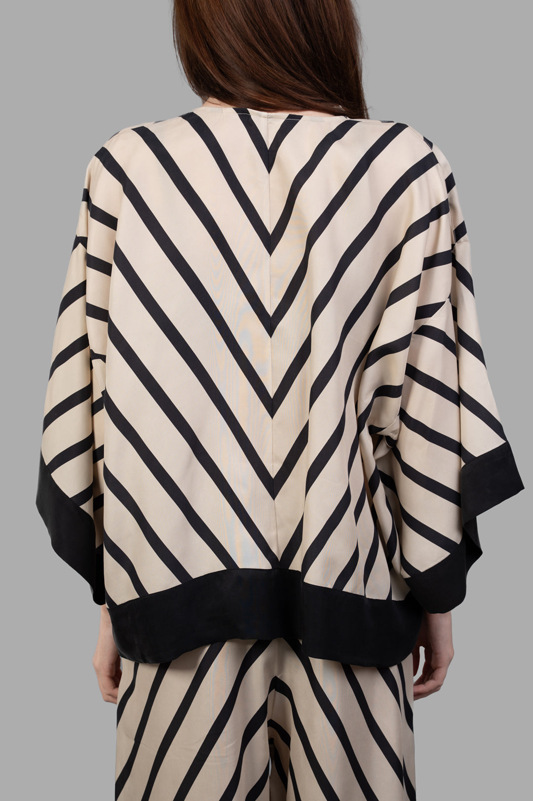 By Malene Birger Cicie Striped Blouse shown from the back, featuring a chevron pattern in ecru and black with cropped sleeves.