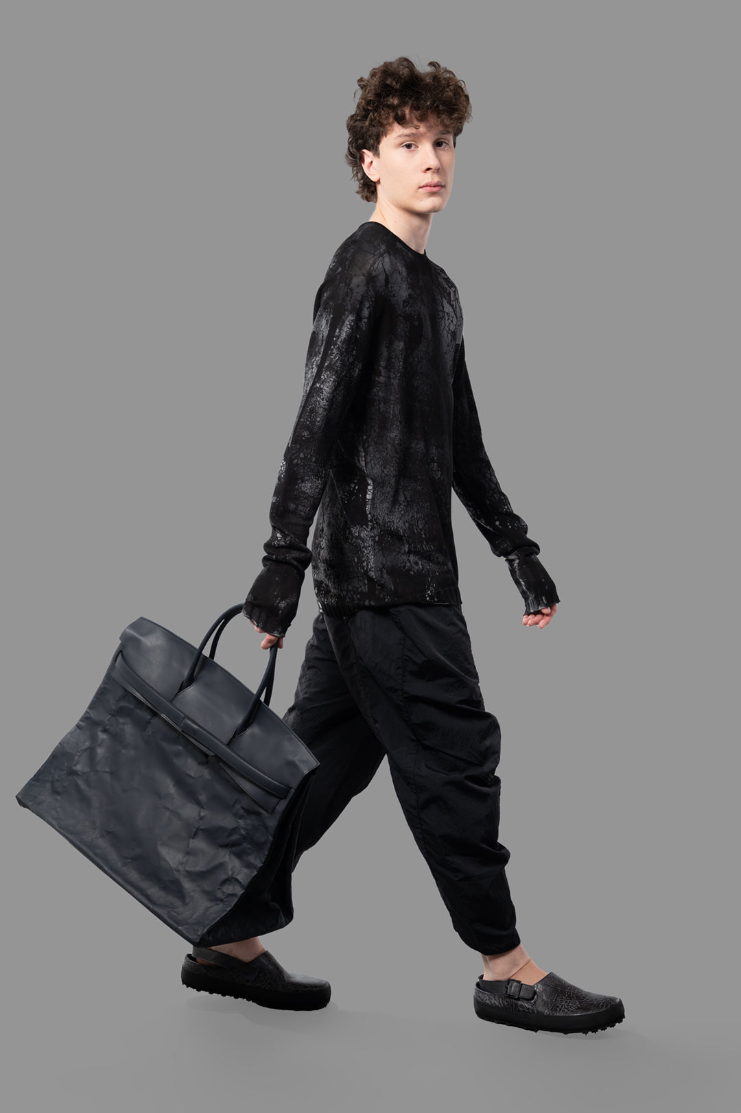 MD 75 Abstract-print Sweater on-model, side view. Model carries black bag, wears black pants and shoes.