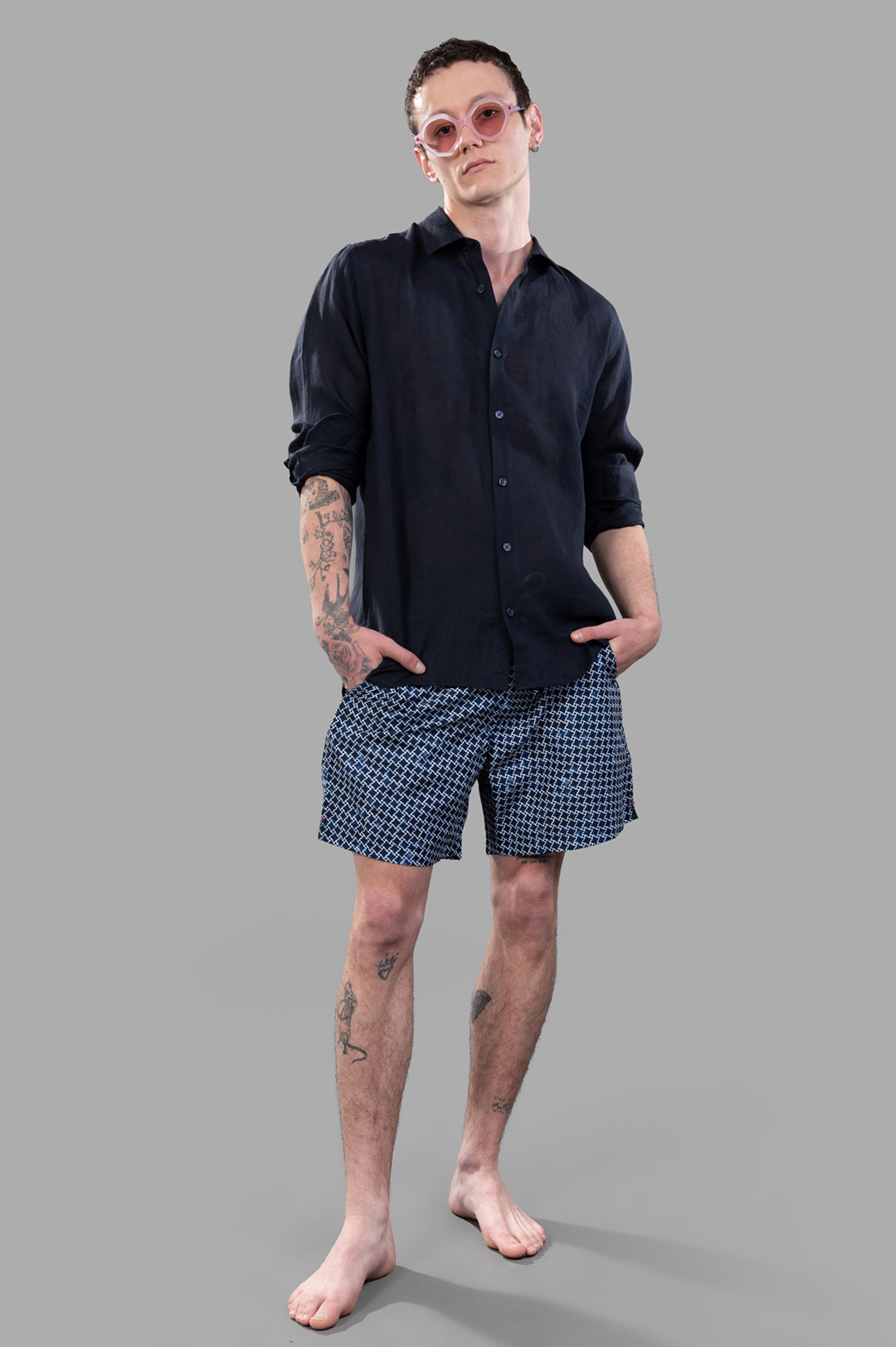 Orlebar Brown navy blue linen shirt on model; front view with rolled sleeves, paired with patterned shorts.