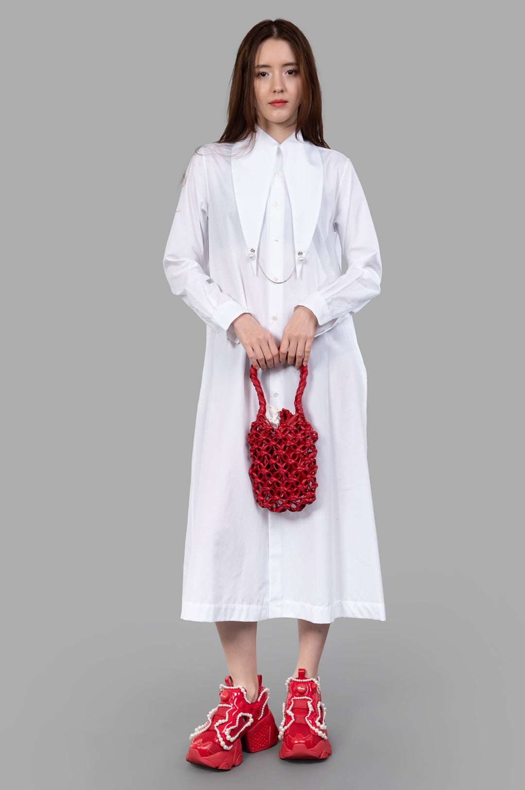 Noir Kei Ninomiya Charm-collar Shirt Dress in white, modeled front view, showcasing pearl charm collar and red accessories.