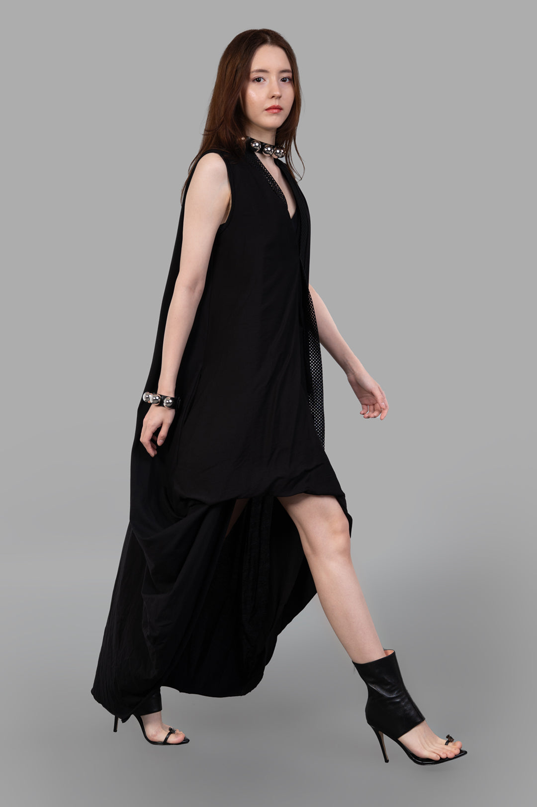 Giovanni Cavagna Asymmetric Dress in Black, side view on model, sleeveless with high neckline and flowing skirt detail.