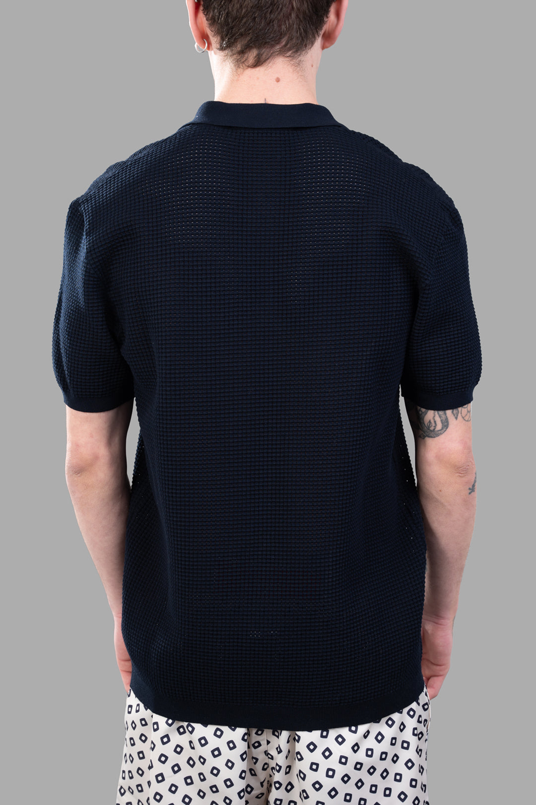 Orlebar Brown Waffle Mesh Polo Shirt, black textured knit seen from the back, showcasing the crafted open collar and sleeves.