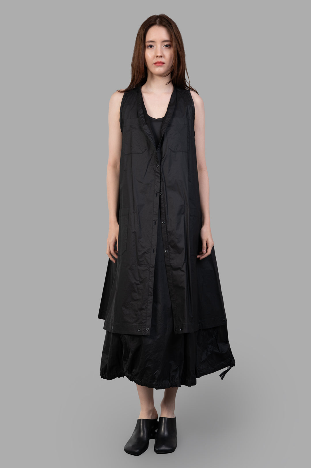 Masnada 2-in-1 Parka on-model front view, long black sleeveless parka layered over dress, button front, A-line hem.