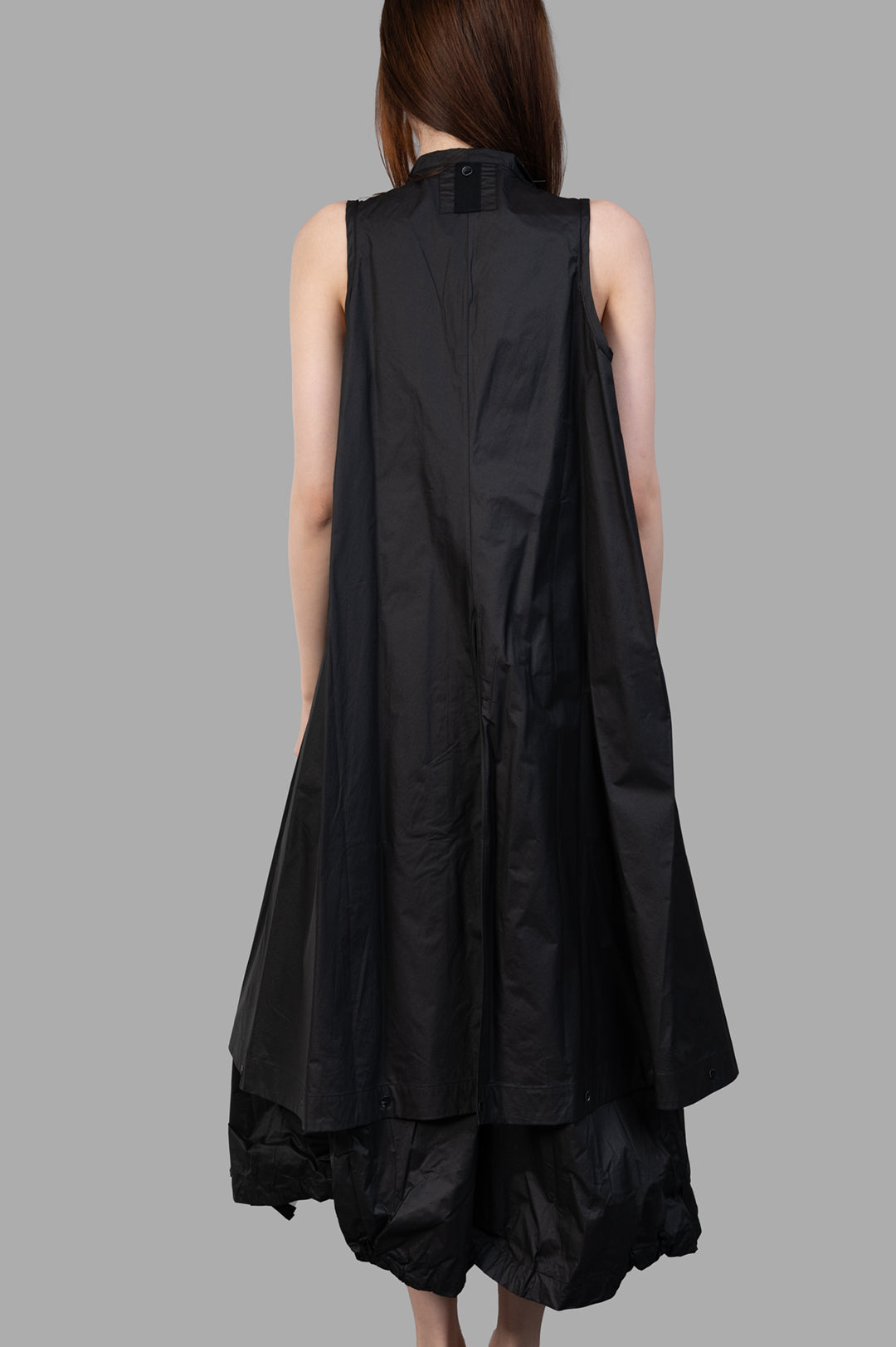 Masnada 2-in-1 Parka back view on-model, sleeveless black parka with flowing A-line shape and layered hem.