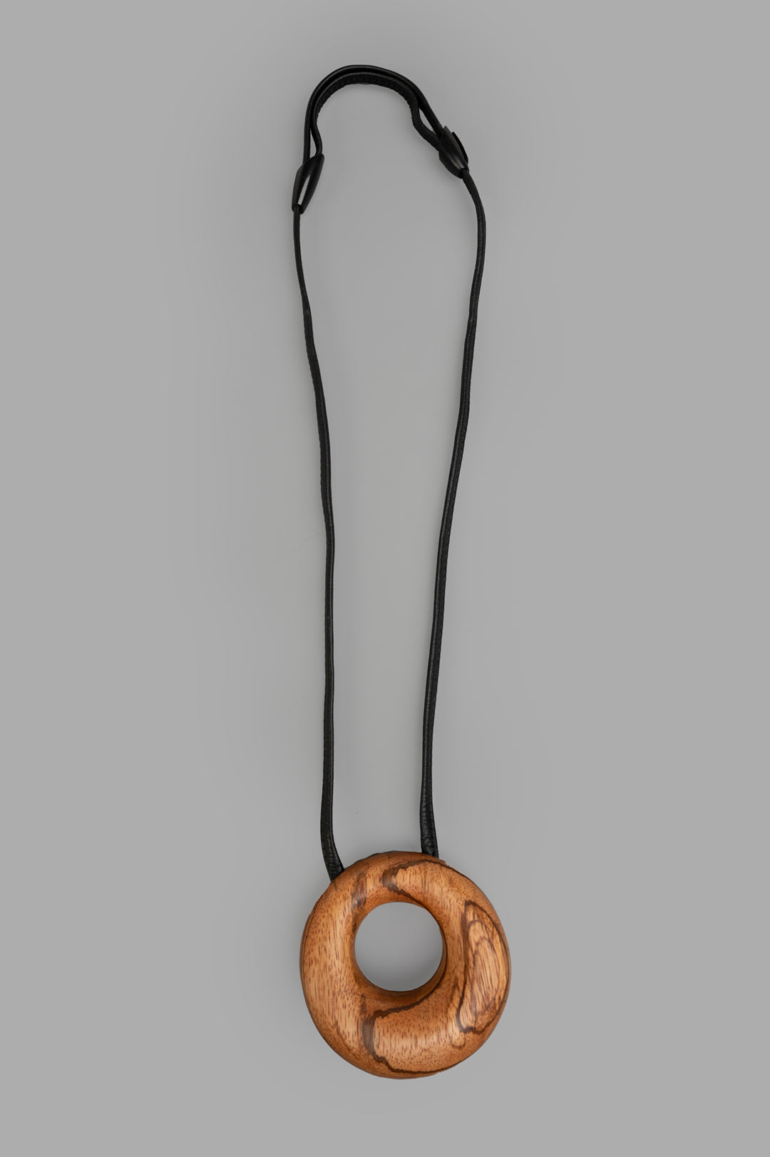 Monies Vala Pendant showcases a round wooden design with a smooth brown texture on a black cord, front view.