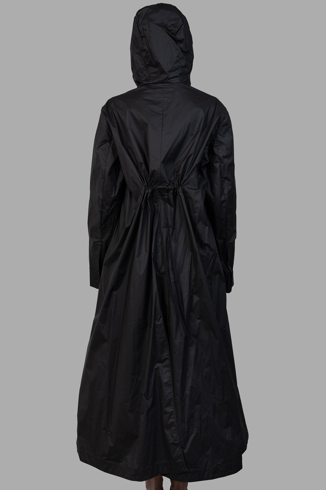 Masnada 2-in-1 Parka back view on-model, black long hooded coat with drawstring waist and draped hem.
