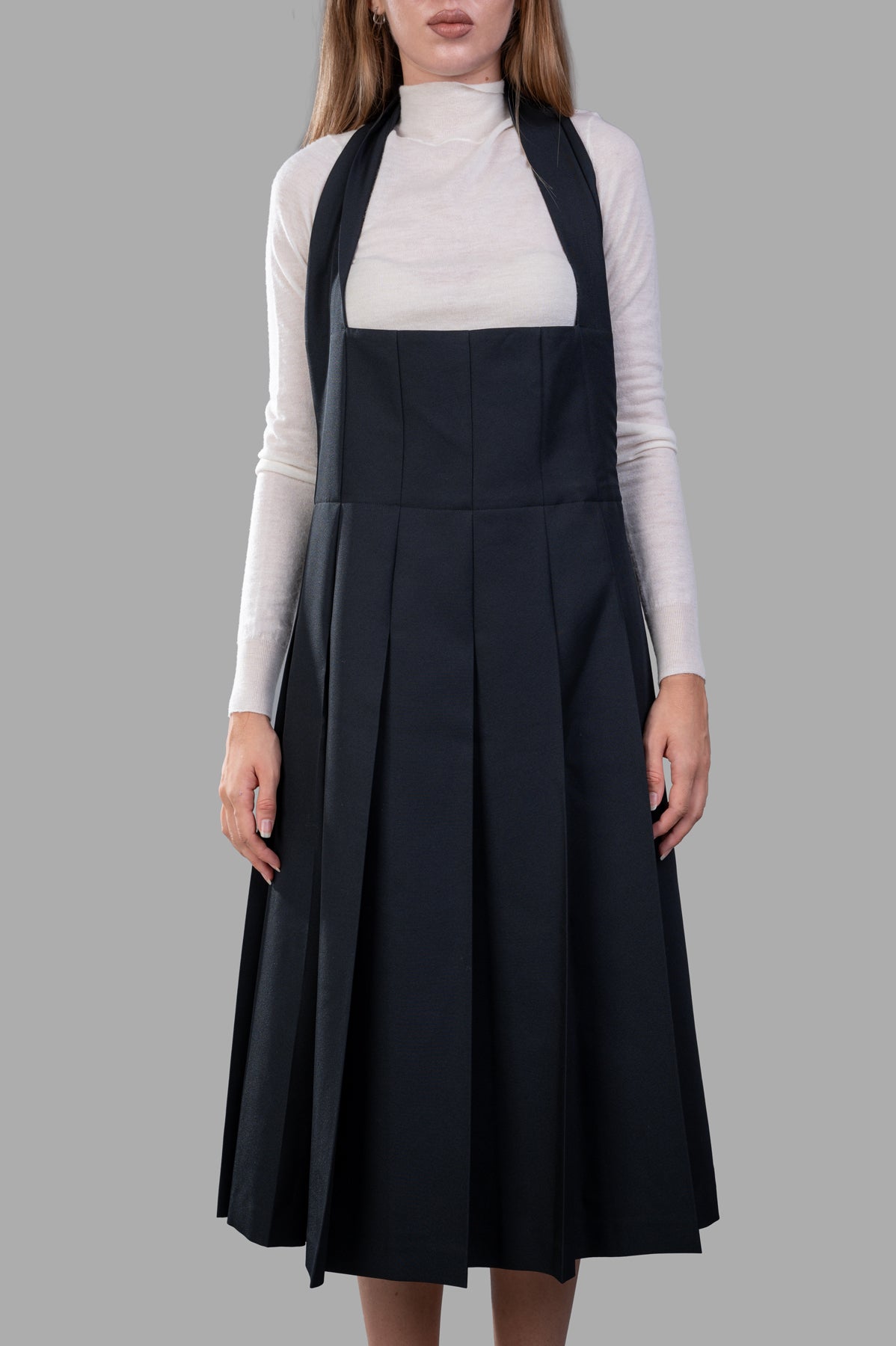 Comme des Garçons Pleated Suspender Dress shown on model, featuring a pleated skirt and halterneck in elegant black.