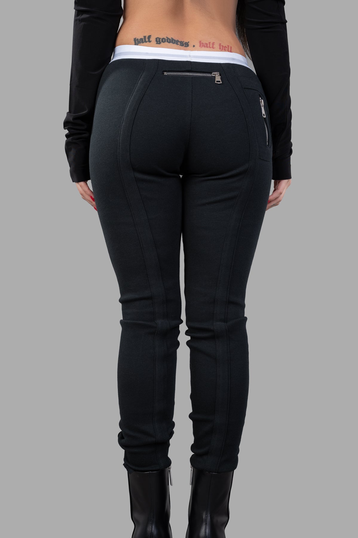 Natasha Zinko Jersey Leggings in black, showcasing the back view with zip detailing and elasticated logo waistband.