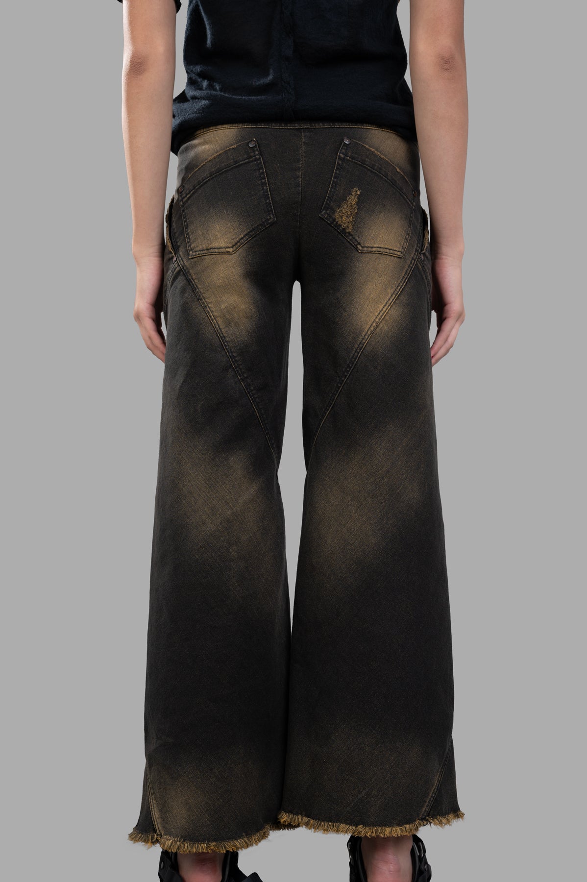 Masnada Faded Bootcut Jeans featuring a wide-leg design, distressed details, and raw hem, showcased from the back.