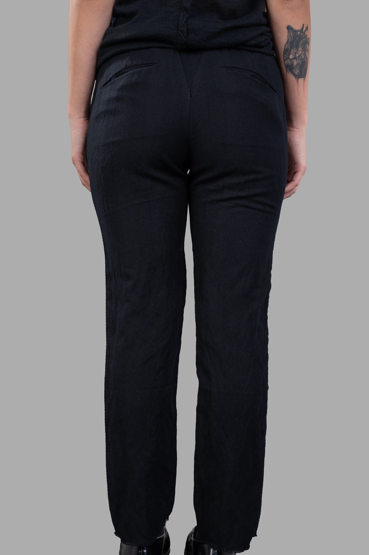 Masnada Slim-cut Trousers in black, showcasing the back view with concealed pockets and frayed hem for a chic look.