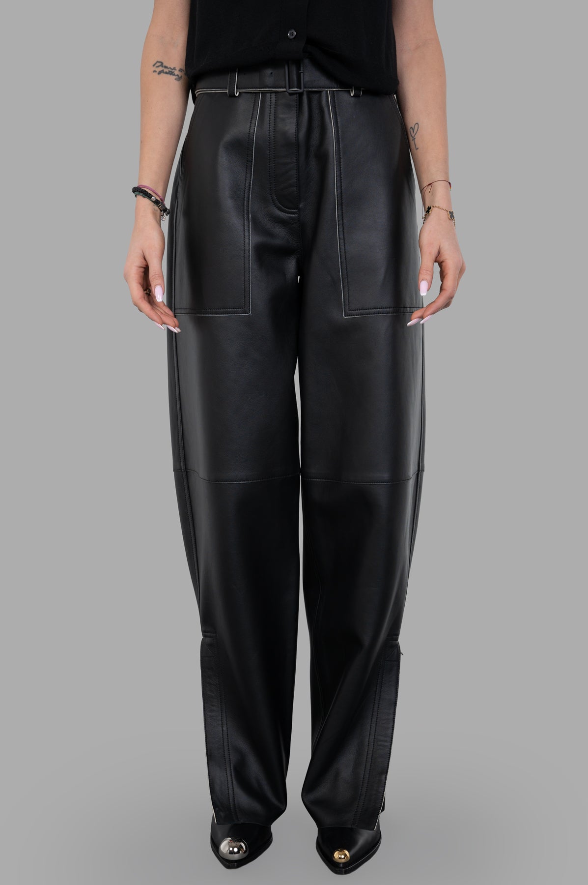 Joseph. Front view of black Nappa Leather Trousers featuring wide tapered legs, buckle belt, and contrasting ivory stitching.