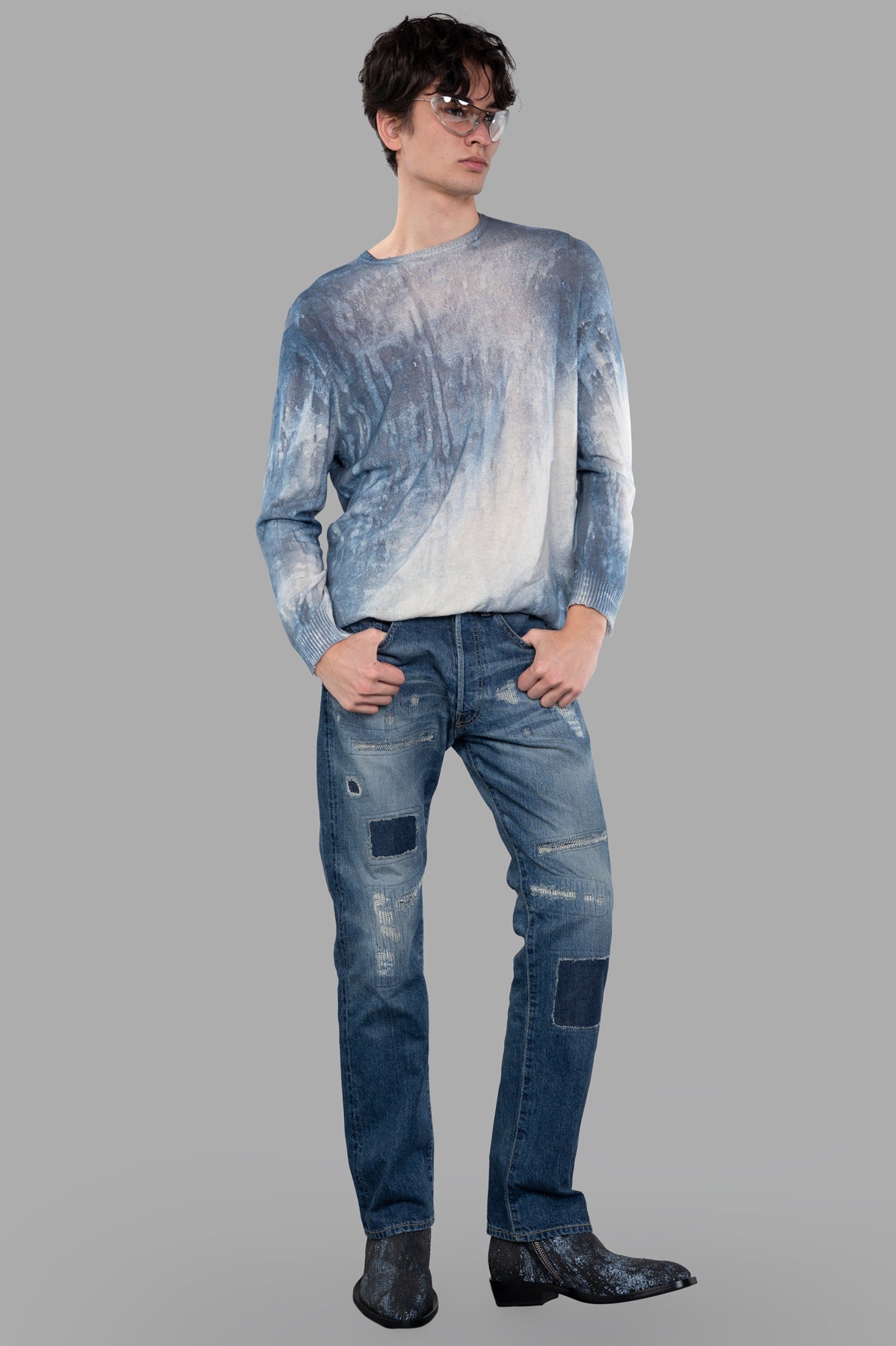 Avant Toi Abstract-print Sweater shown from the front on a model, paired with jeans and boots against a gray background.