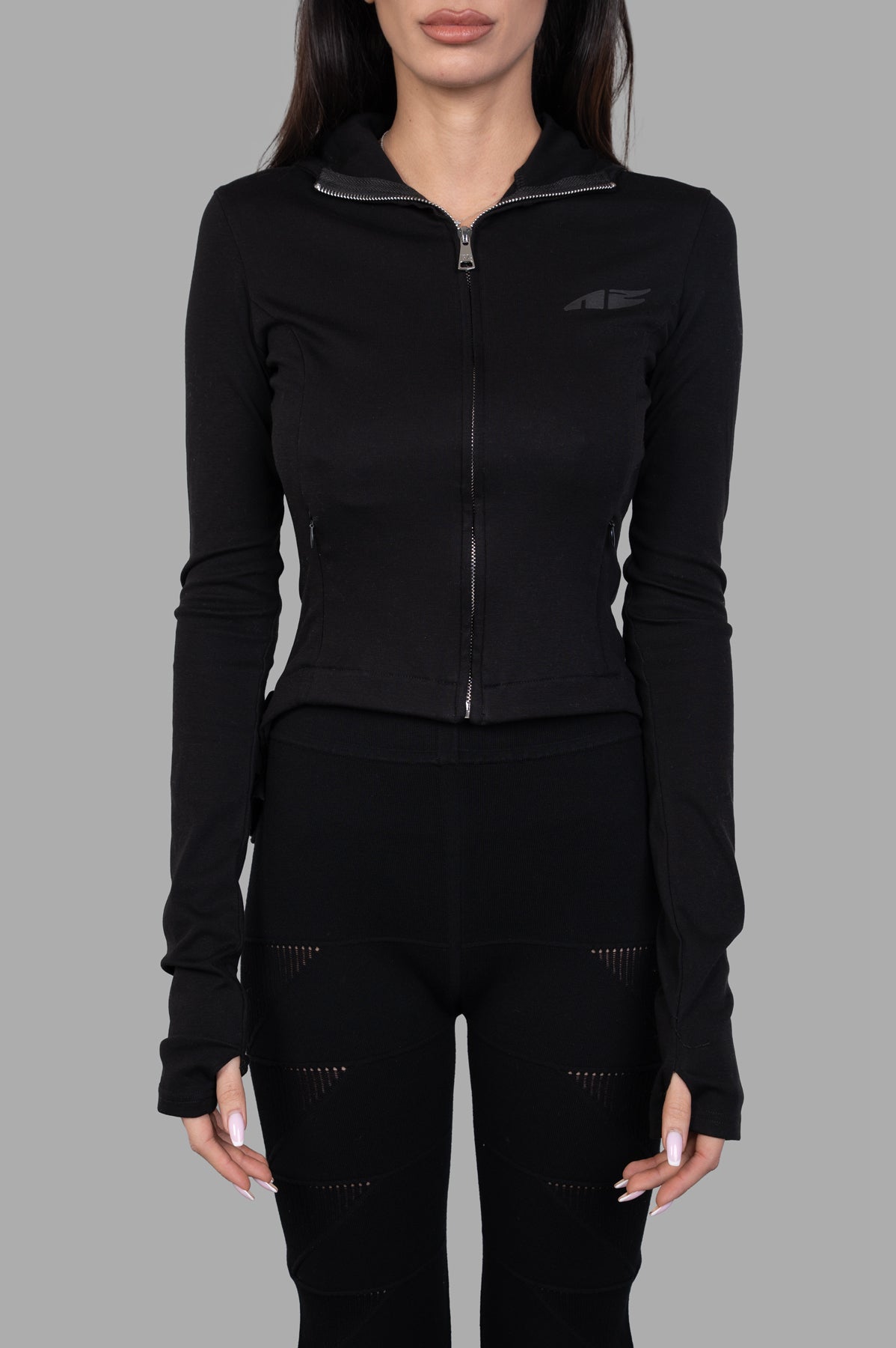 Natasha Zinko Ruffled Hooded Jacket in black, featuring a fitted zip-up design and long sleeves, showcased on a model.