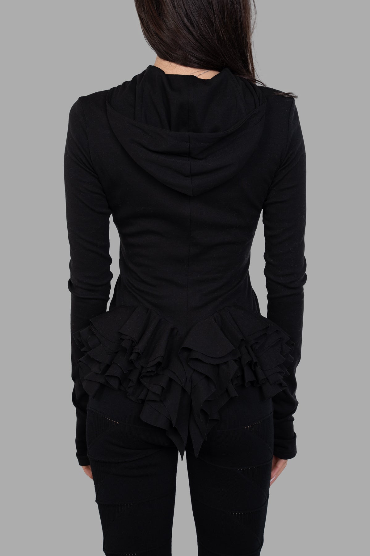 Natasha Zinko Ruffled Hooded Jacket viewed from the back, highlighting its unique ruffled detail and snug fit in black.