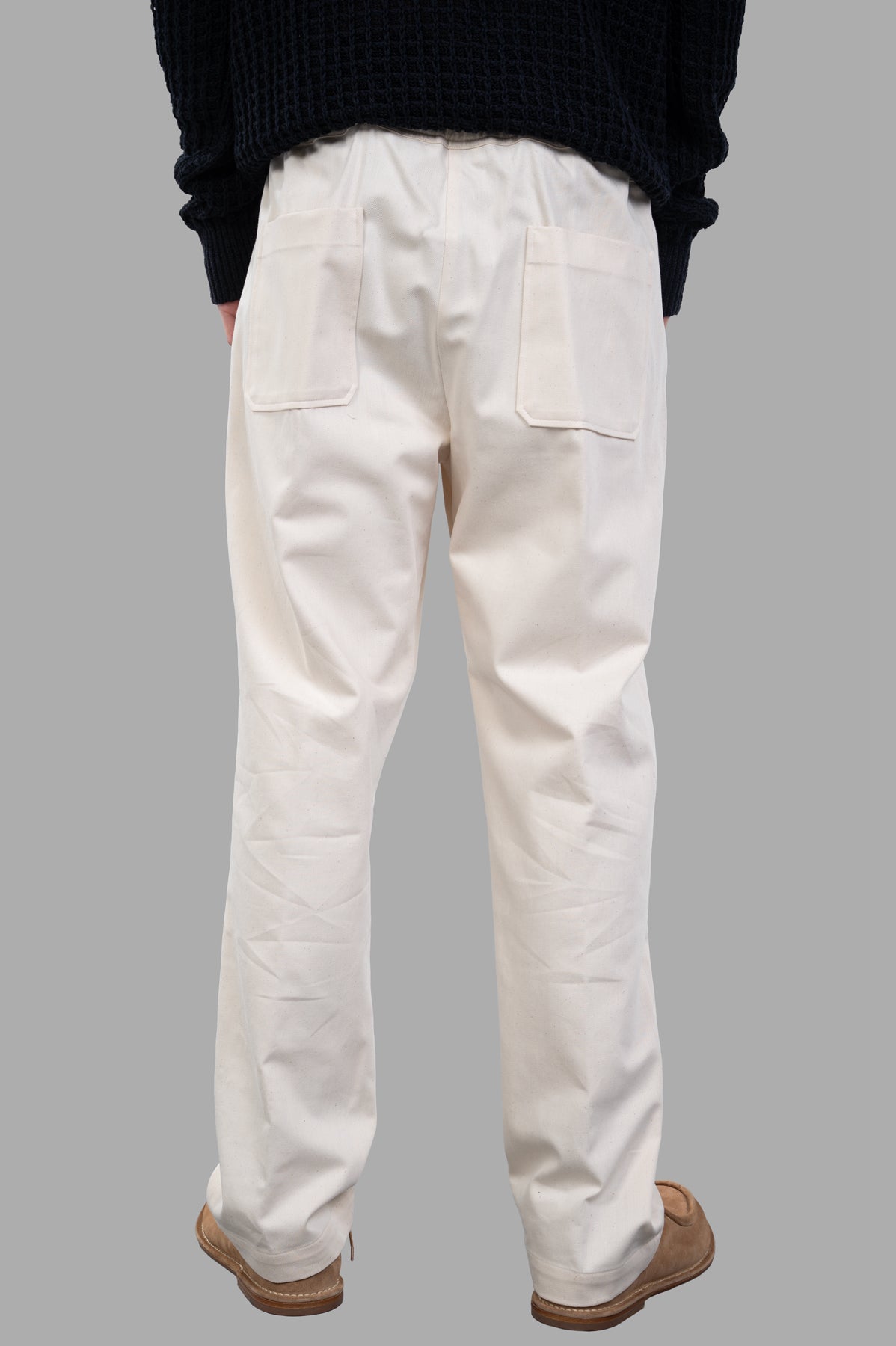 AION. Drawstring Pants in ecru, showcasing the back view with elasticized waist and convenient pockets for comfort.