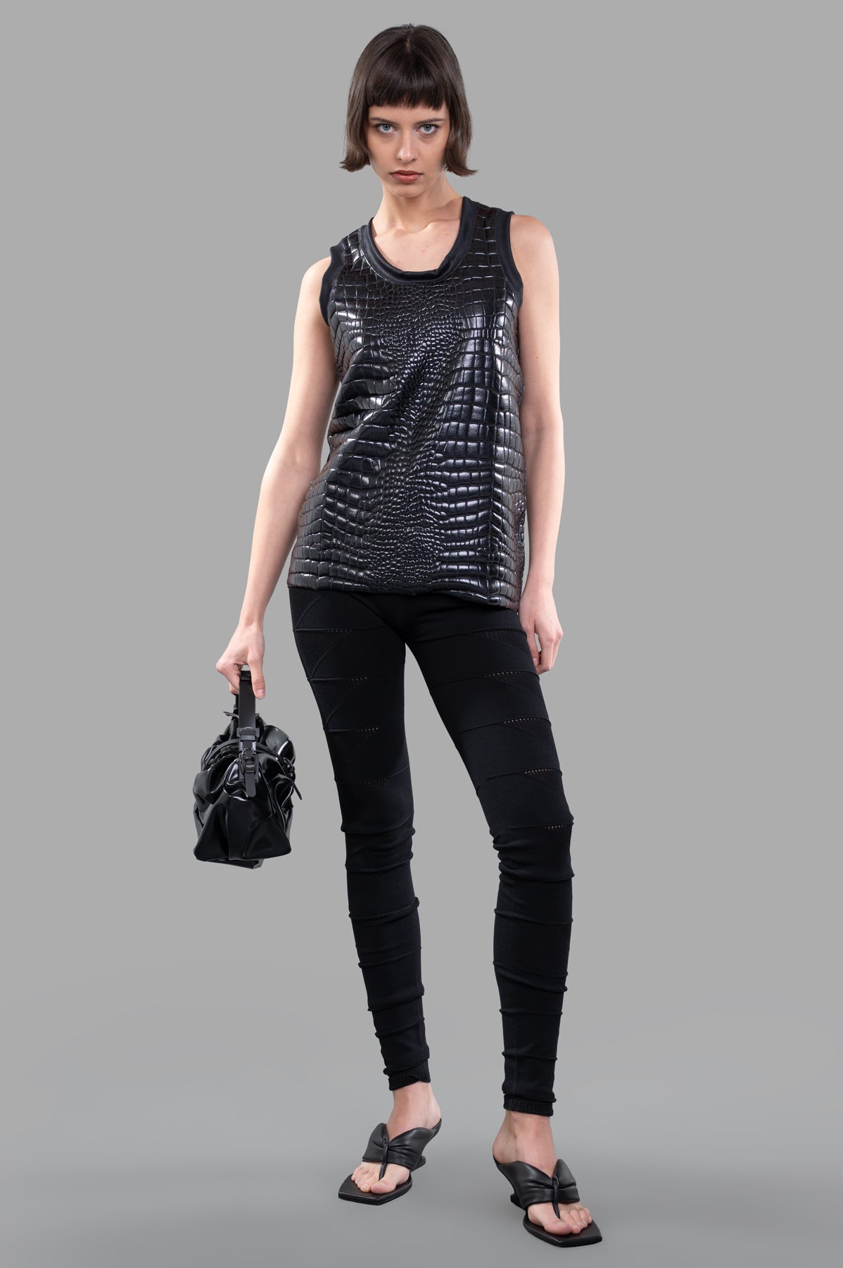 Junya Watanabe Crocodile-embossed Top, front view, black sleeveless design, paired with black pants, model holding handbag.