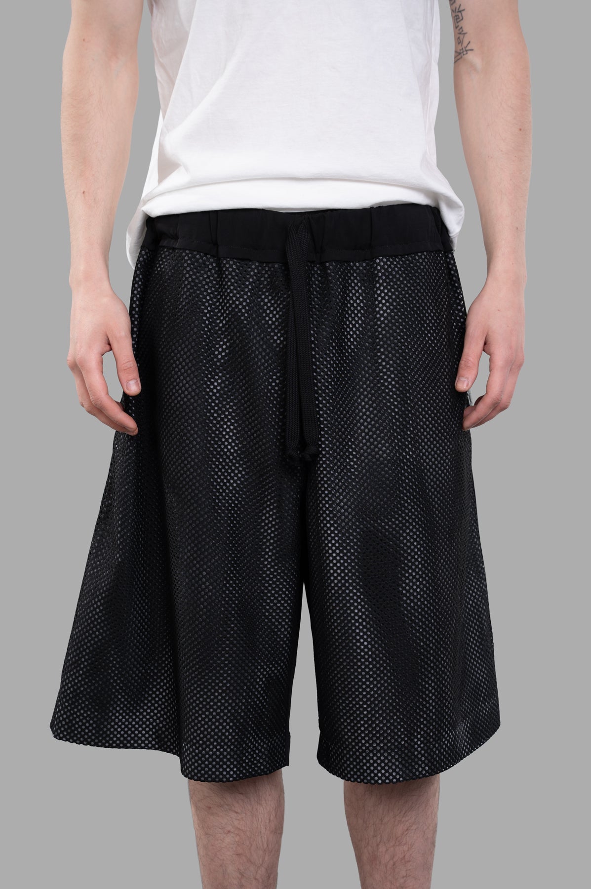 Giovanni Cavagna Perforated Shorts in black, featuring a breathable, relaxed fit fabric shown worn from the front.