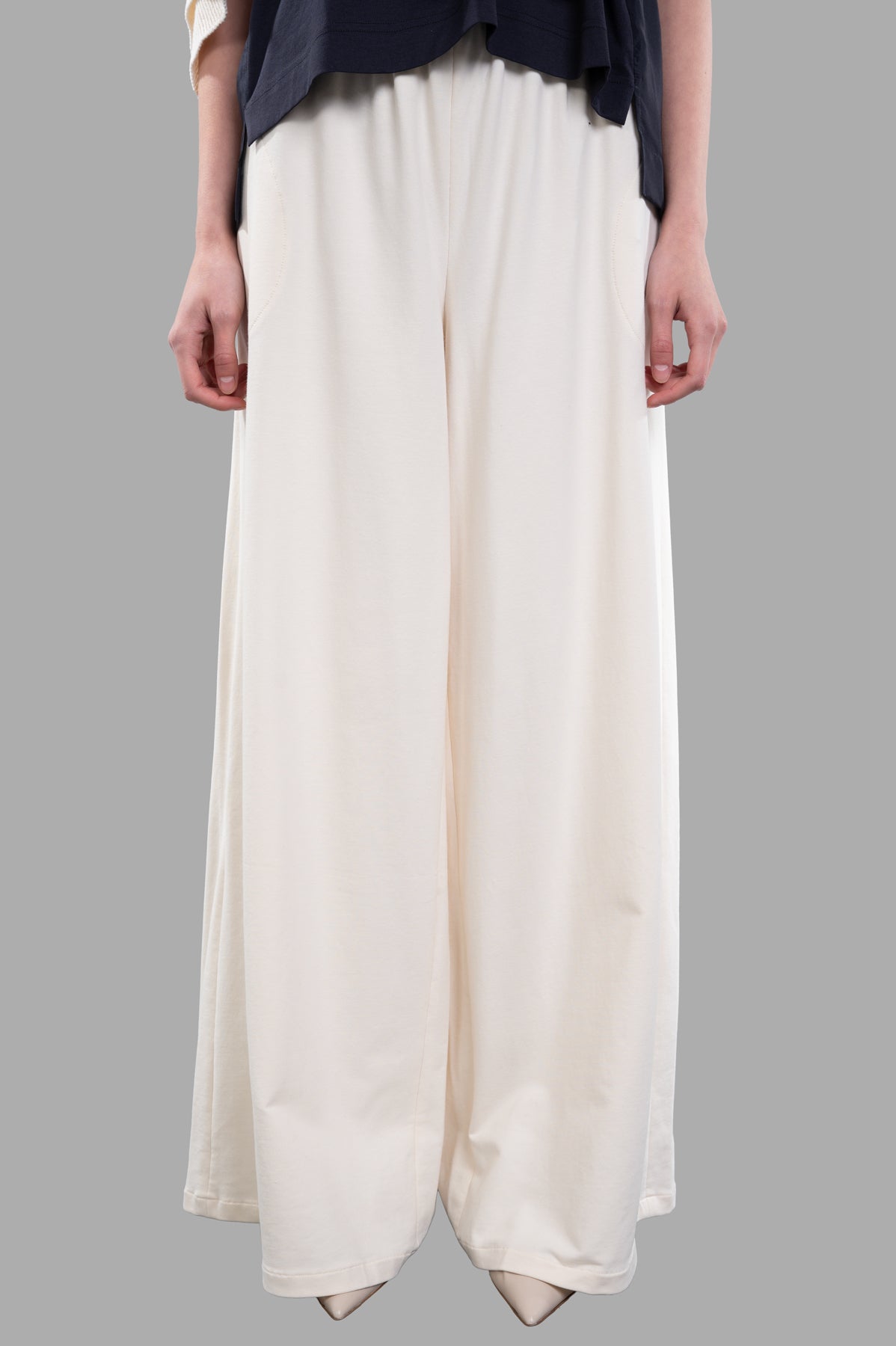 Norma Kamali Wide-leg Trousers in ecru featuring an elasticized waist, shown from the front with side pockets, soft texture.