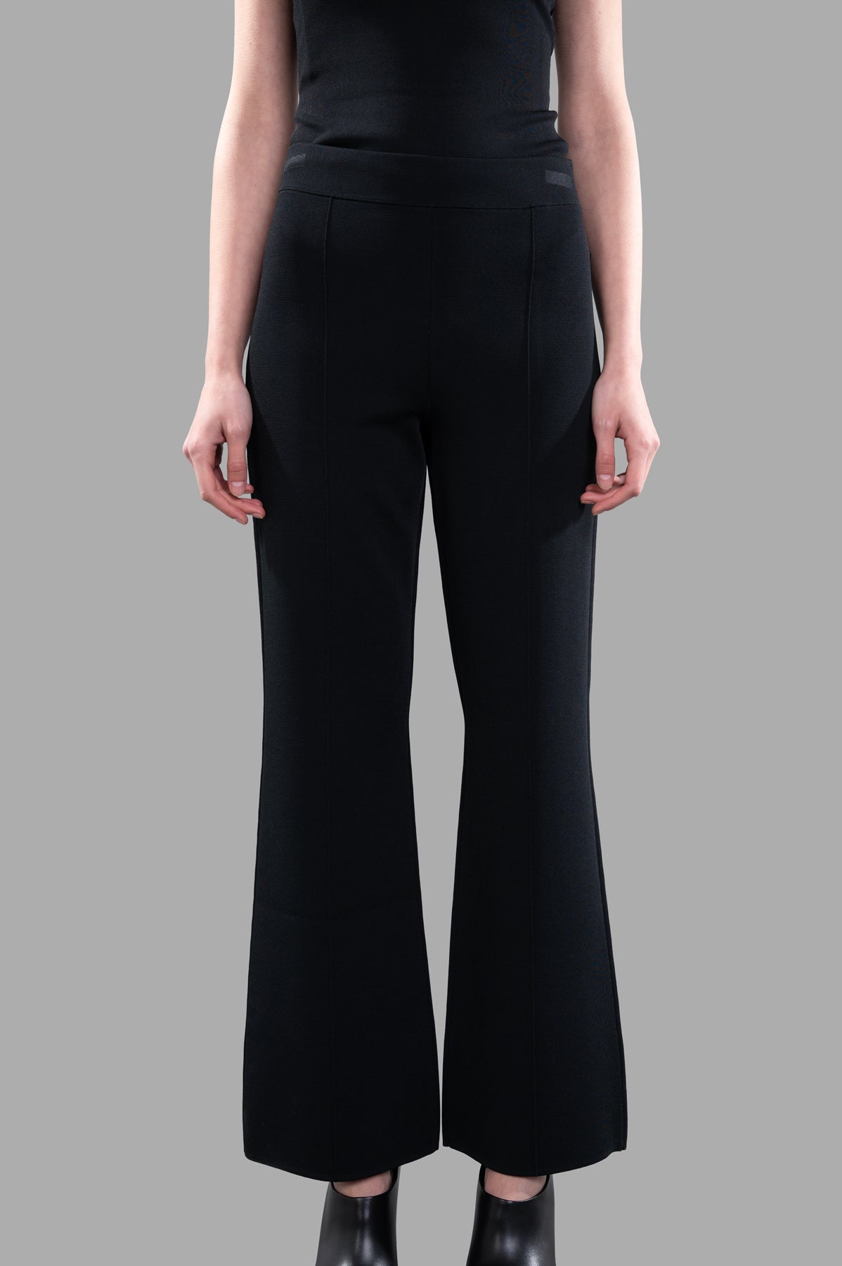 Joseph Stretch Knit Trousers in black, featuring an elasticized waistband and sleek flared silhouette, shown from the front.