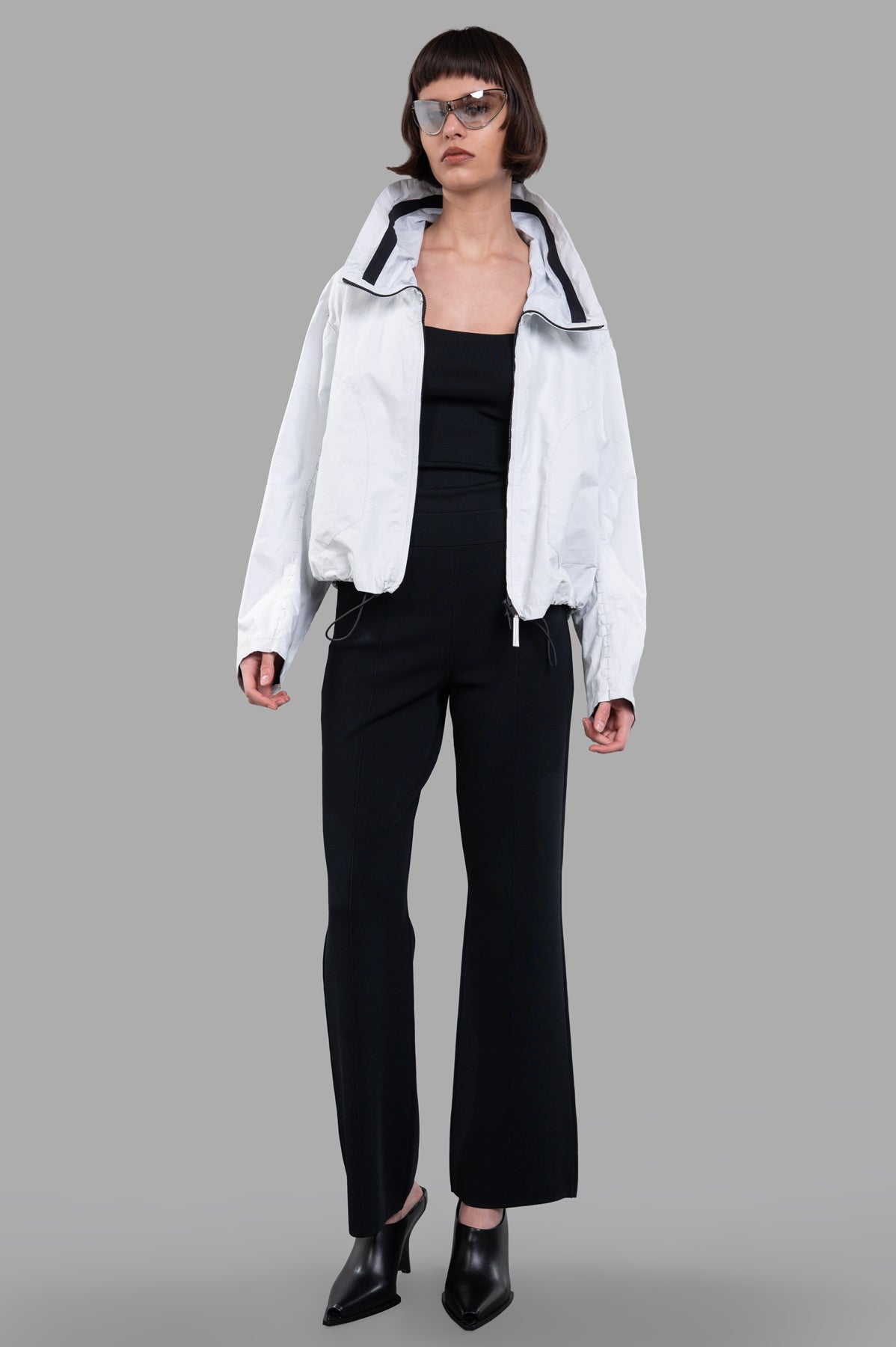 Isaac Sellam Cropped Windbreaker Jacket, off-white with zipper and tube neckline, shown on-model for a sleek front view.