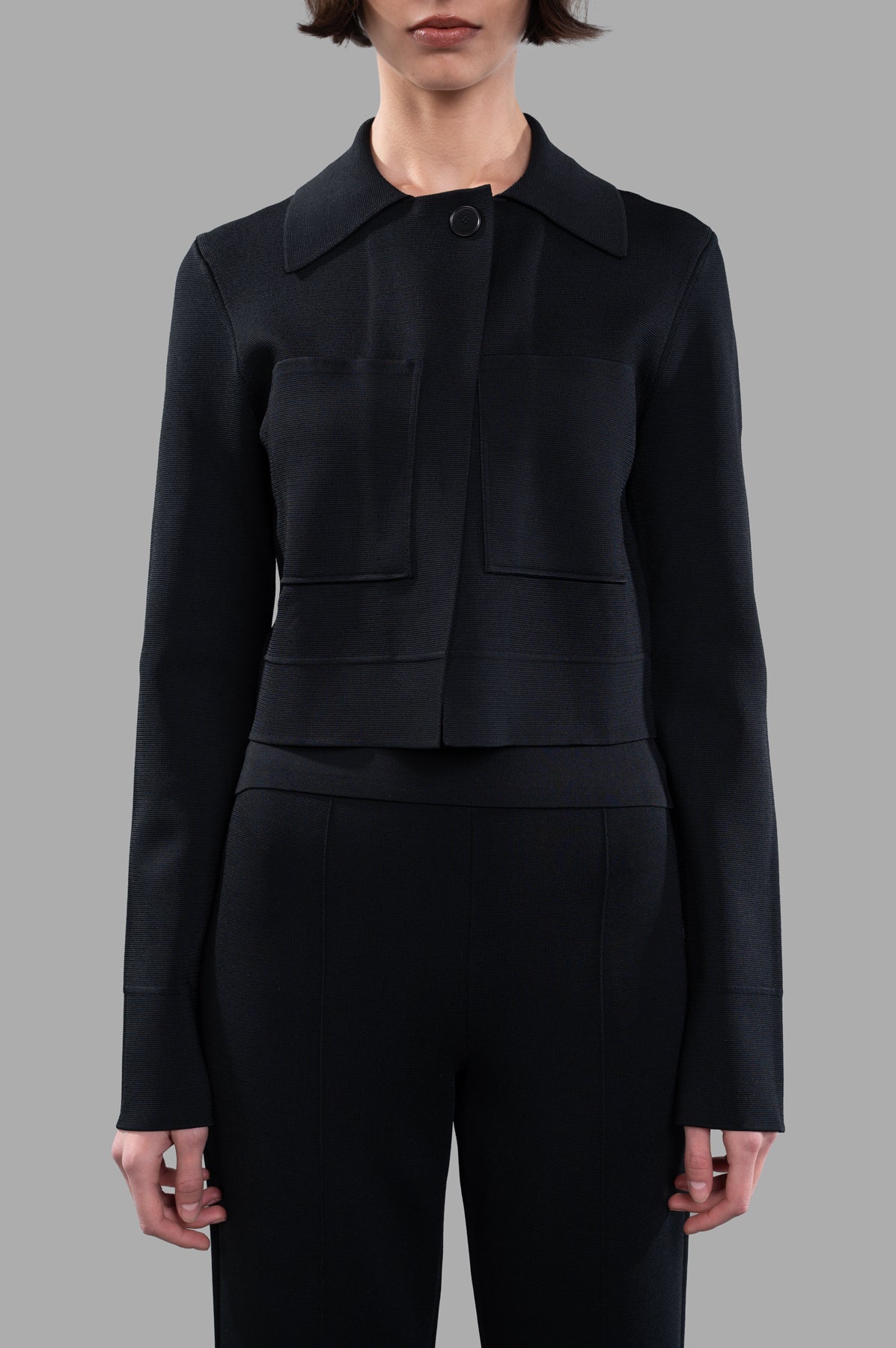 Joseph Stretch-zip Jacket displayed on a model, featuring a boxy cut, zip closure, and two front pockets in black knit.