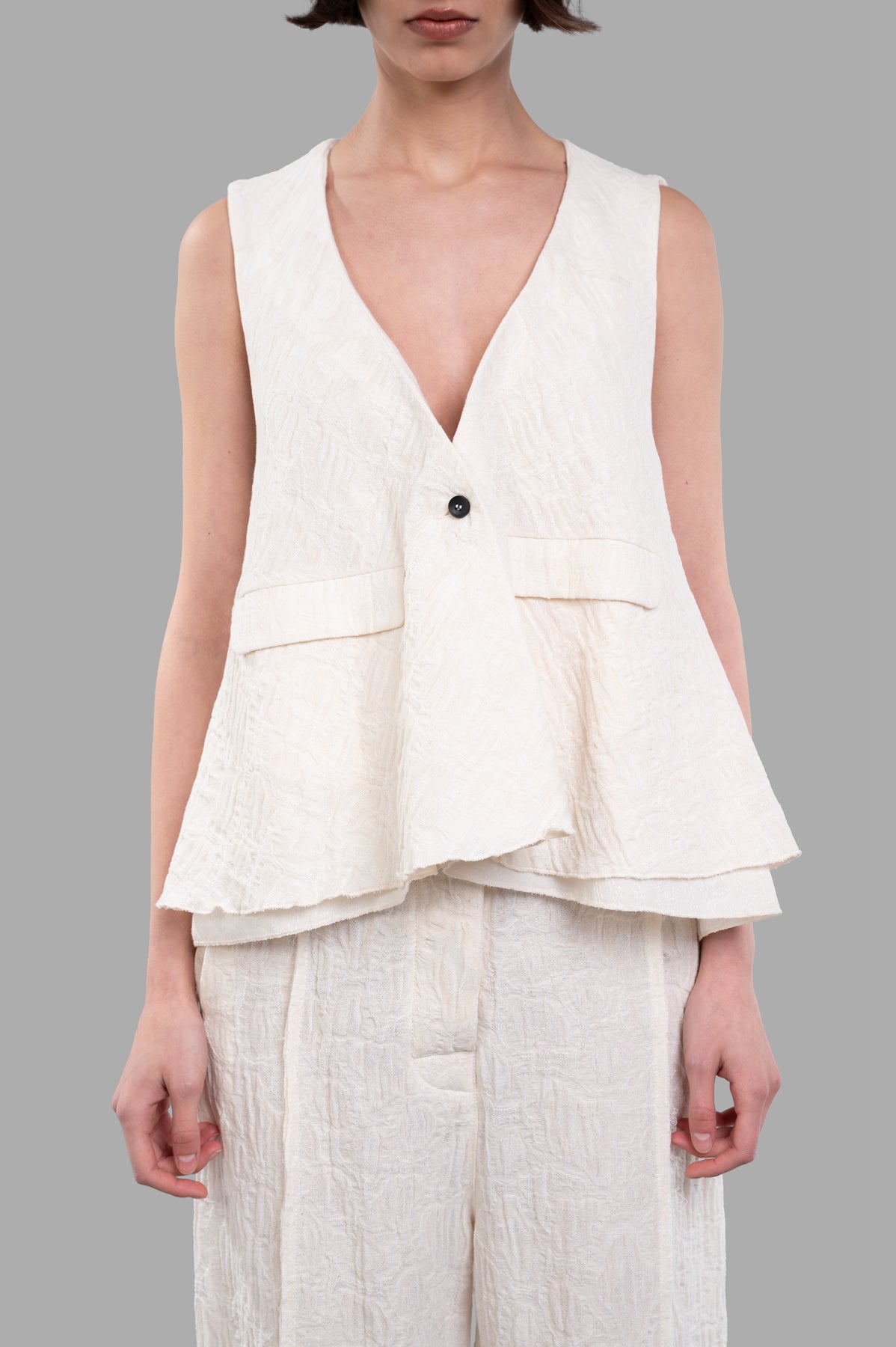 Marc Point Textured Vest in ecru features a V-neck and A-line cut, showcasing its unique textured fabric on a model.