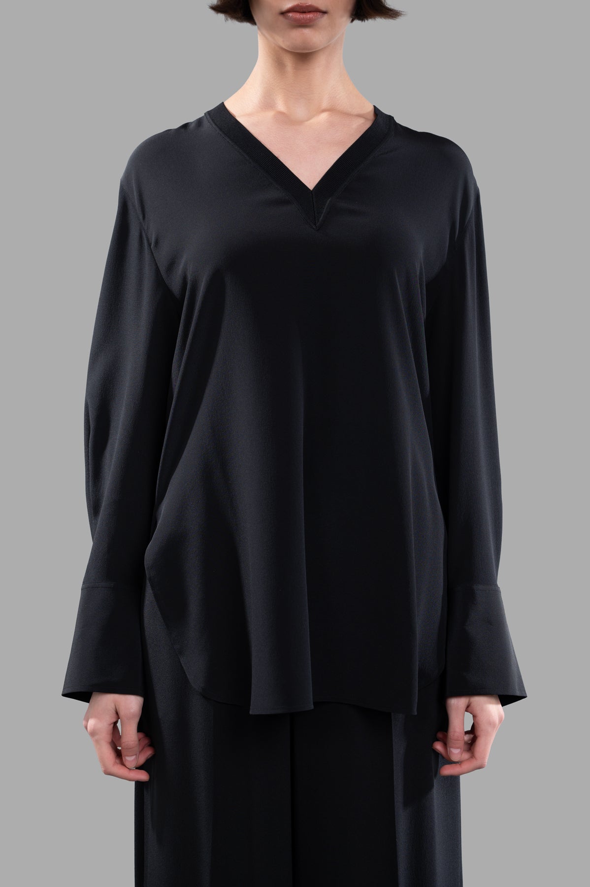 Joseph V-neck Silk Blouse in black, featuring a flowing design and rib-knit neckline, modeled from the front for detail.