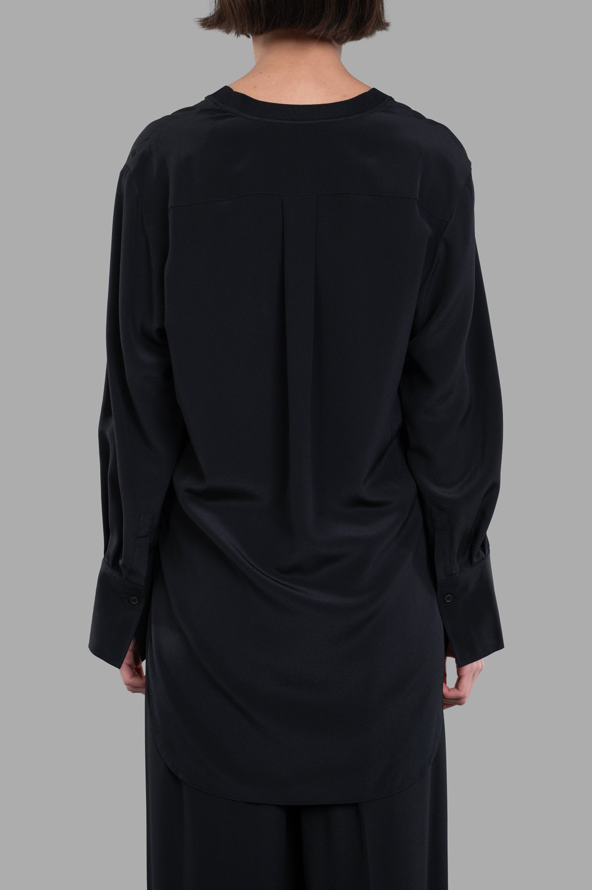 Joseph V-neck Silk Blouse in black, showcasing the back detail and flowing silk texture on a model. Perfect for any occasion.
