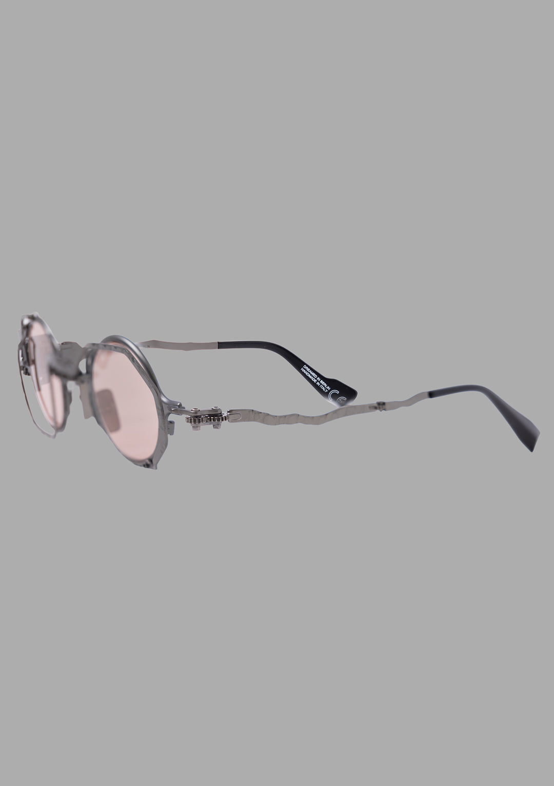Kuboraum unisex gunmetal sunglasses with light pink lenses, three-quarter side view showing wavy metal temples.