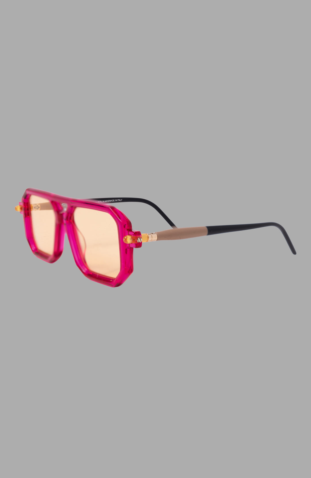 Kuboraum unisex magenta sunglasses, three-quarter view showing thick acetate rims and gold-tone hinge detail.