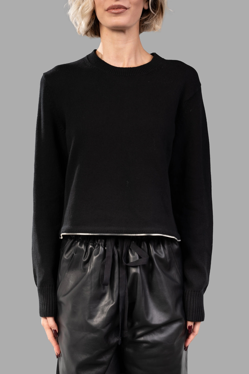 Front close-up of black cropped crewneck knit with metal zip at hem and ribbed trims