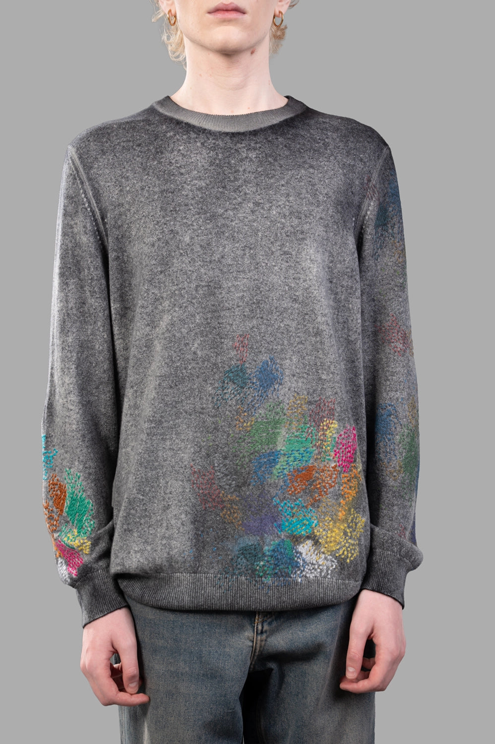 Front close-up of grey cashmere sweater showing multicolour hand-painted abstract motifs and ribbed crew neck
