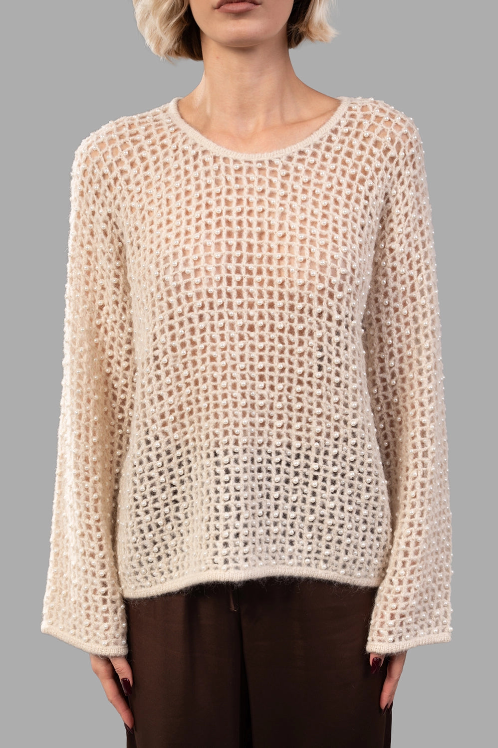 Front close-up of open-mesh sweater showing pearl accents, round neckline and airy knit texture